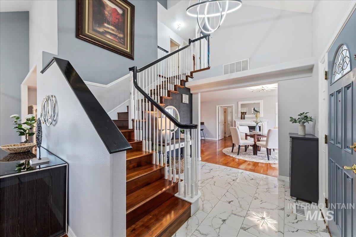 Entryway featuring light marble finish floors, stairway, and a towering ceiling