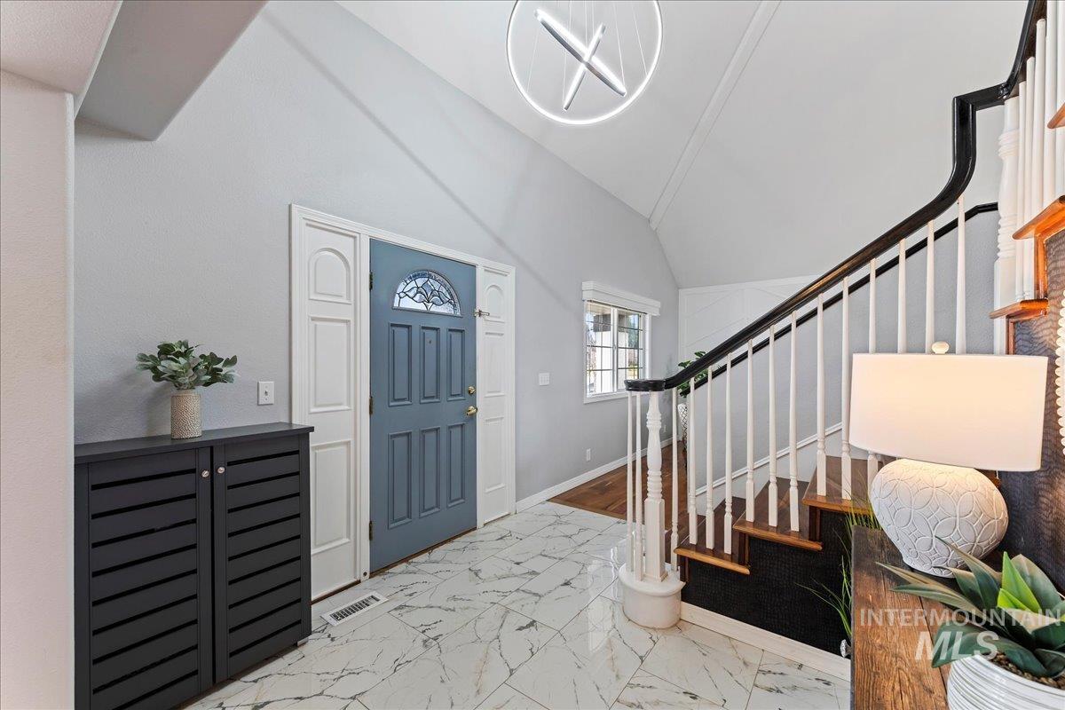 Entryway featuring marble finish floors, stairway, and vaulted ceiling