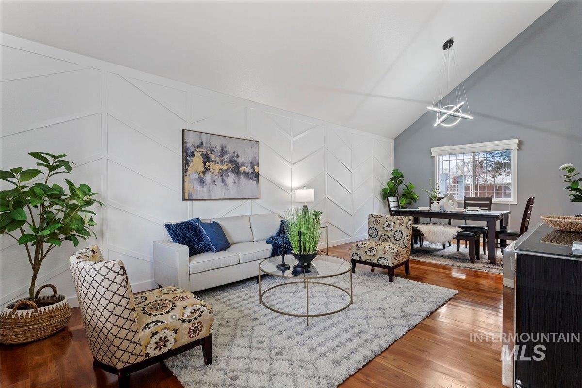Living room with an accent wall, wood finished floors, a decorative wall, and high vaulted ceiling