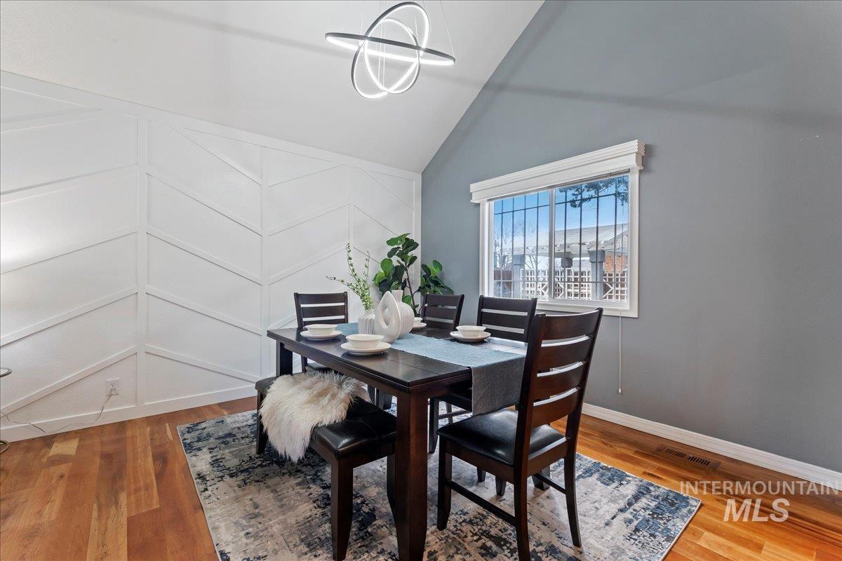Dining space featuring vaulted ceiling, light wood finished floors, and a chandelier