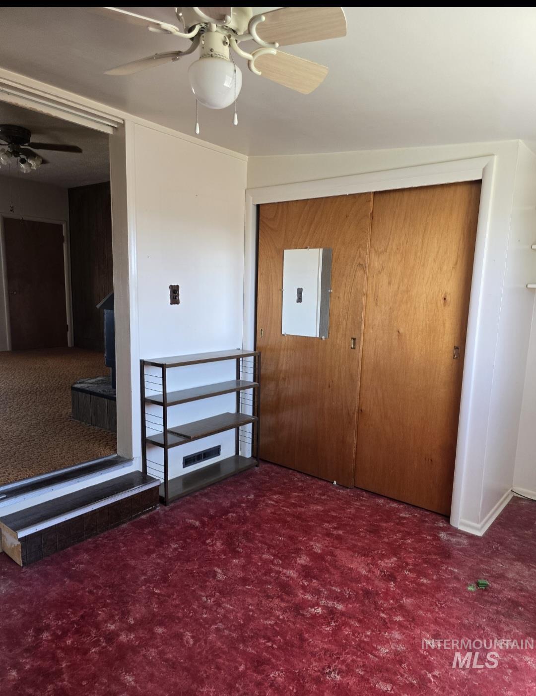 Unfurnished bedroom with dark colored carpet, a closet, and a ceiling fan