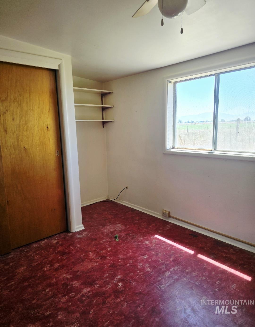 Unfurnished bedroom featuring dark colored carpet, a closet, and ceiling fan