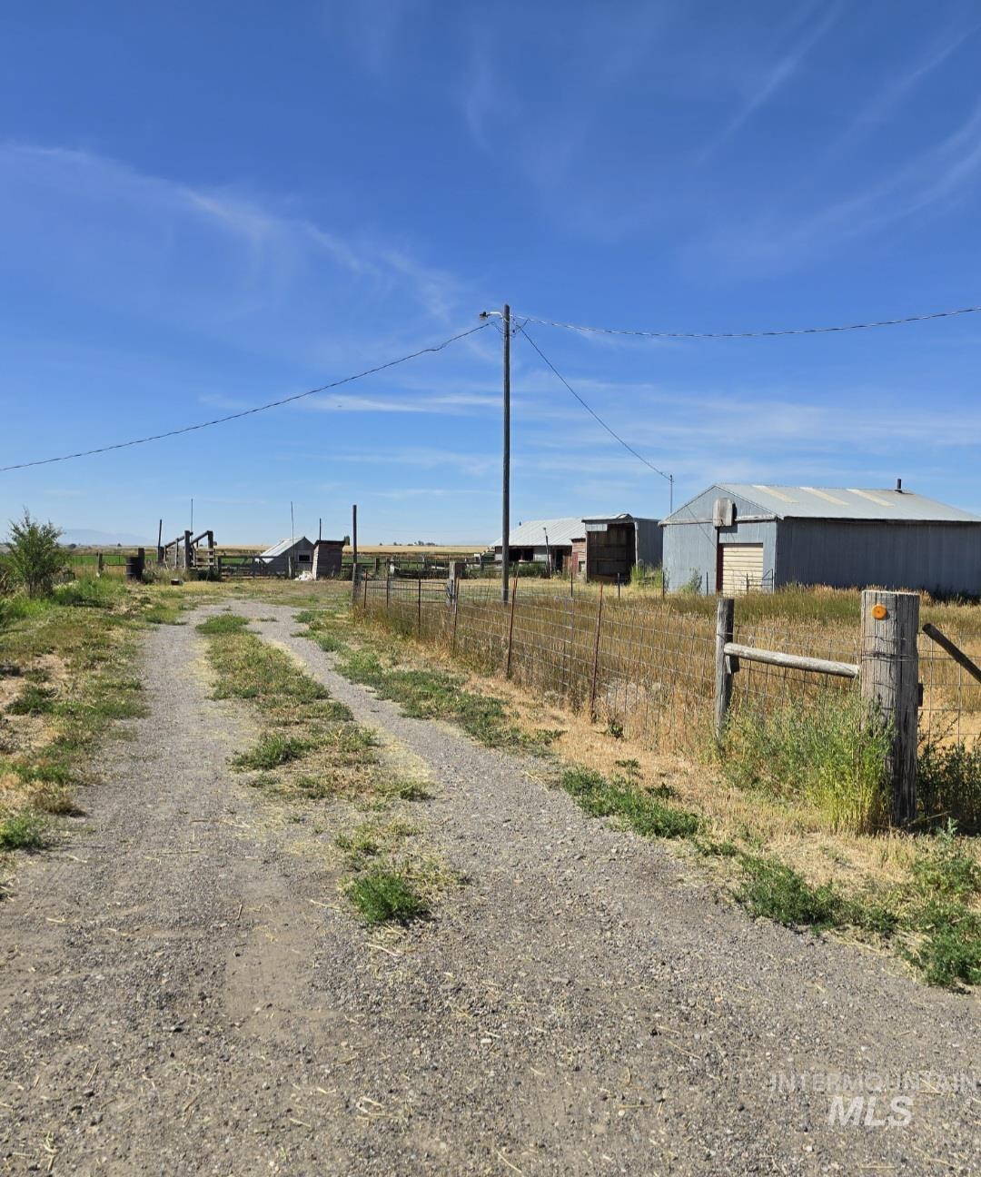 View of dirt / gravel road with an outbuilding and a rural view