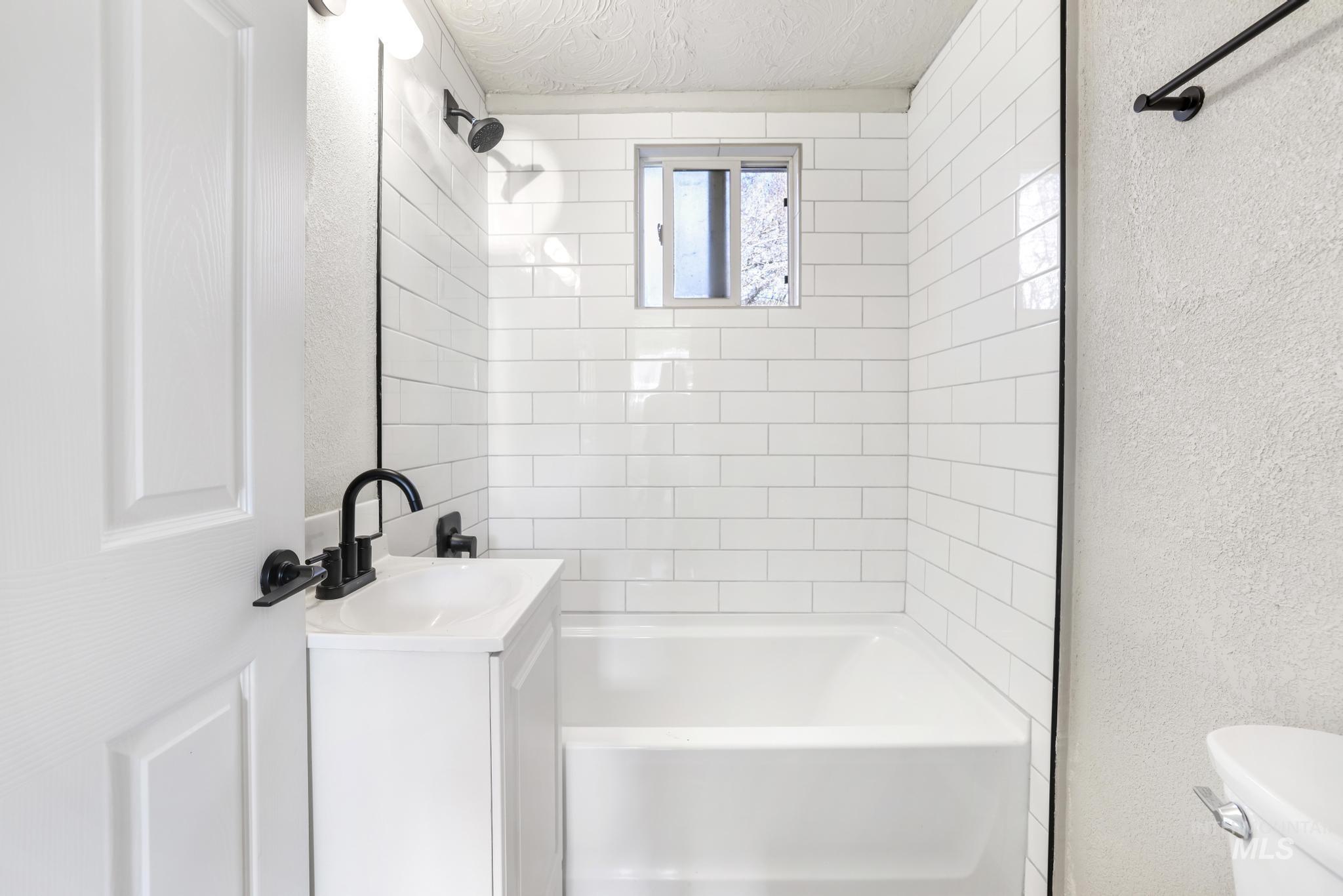 Full bath featuring a textured wall, vanity, tub / shower combination, and a textured ceiling