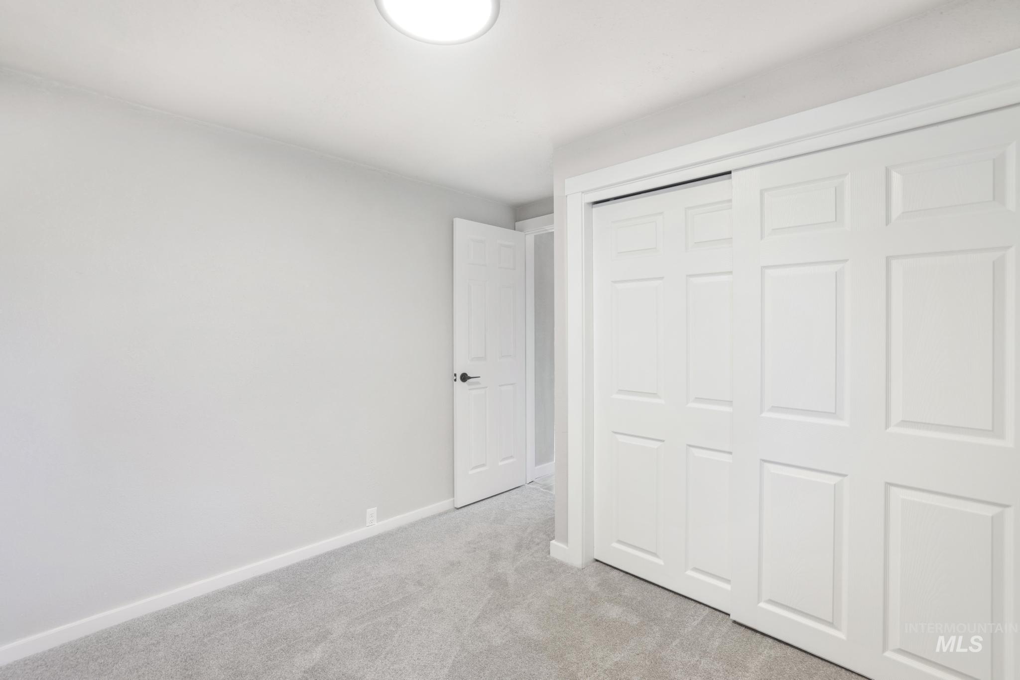 Unfurnished bedroom featuring light carpet and a closet