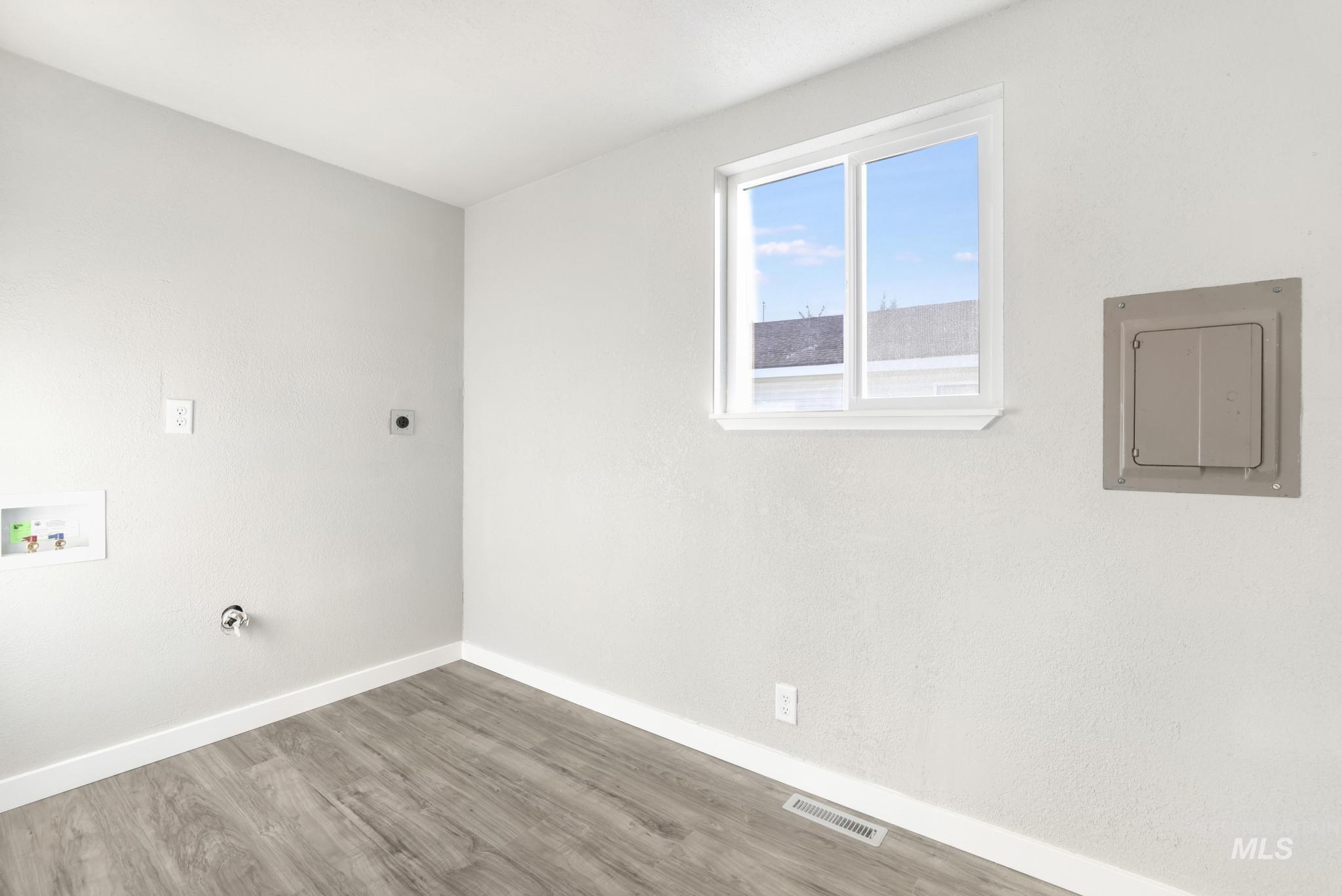 Washroom featuring wood finished floors, electric panel, hookup for a washing machine, electric dryer hookup, and gas dryer hookup
