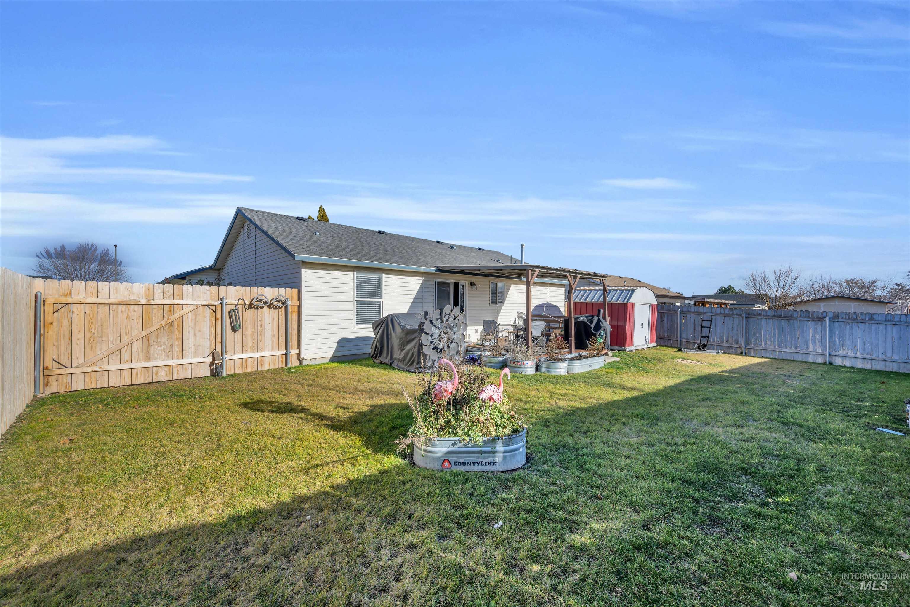 Rear view of property featuring a fenced backyard, a patio area, a storage unit, and a gate