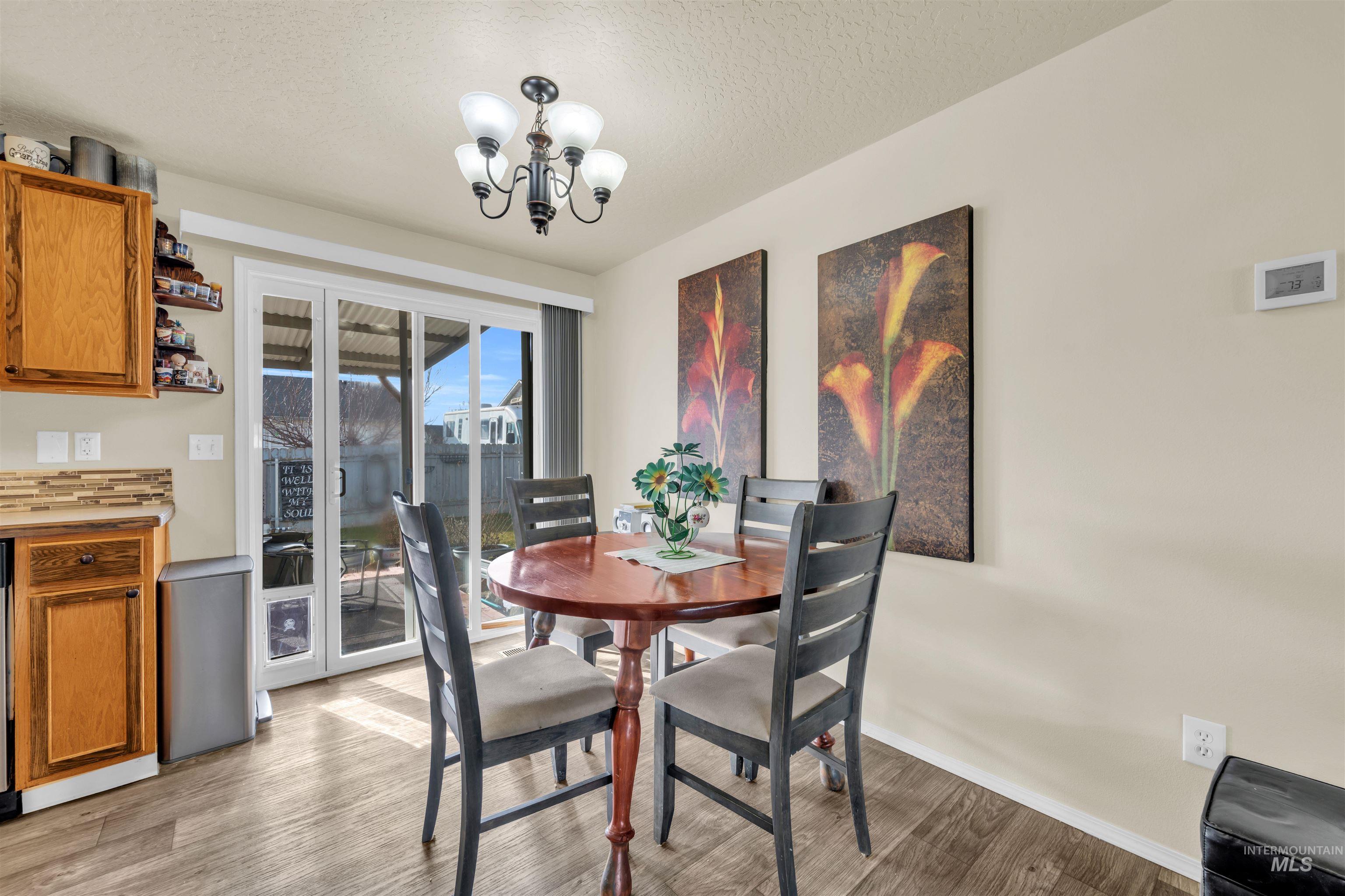 Dining space featuring a chandelier, light wood finished floors, and a textured ceiling