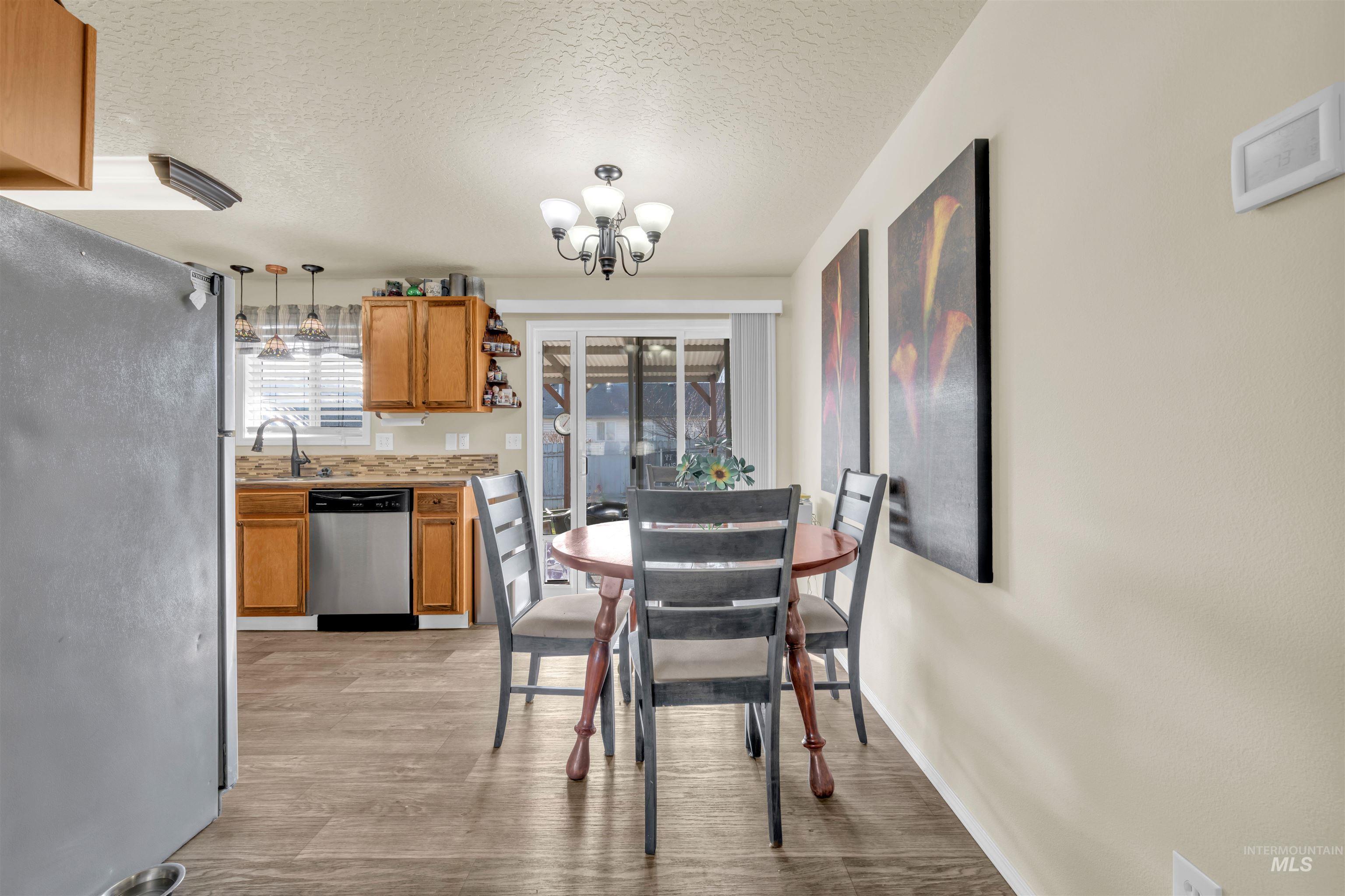 Dining room with a textured ceiling, light wood-style floors, and a chandelier