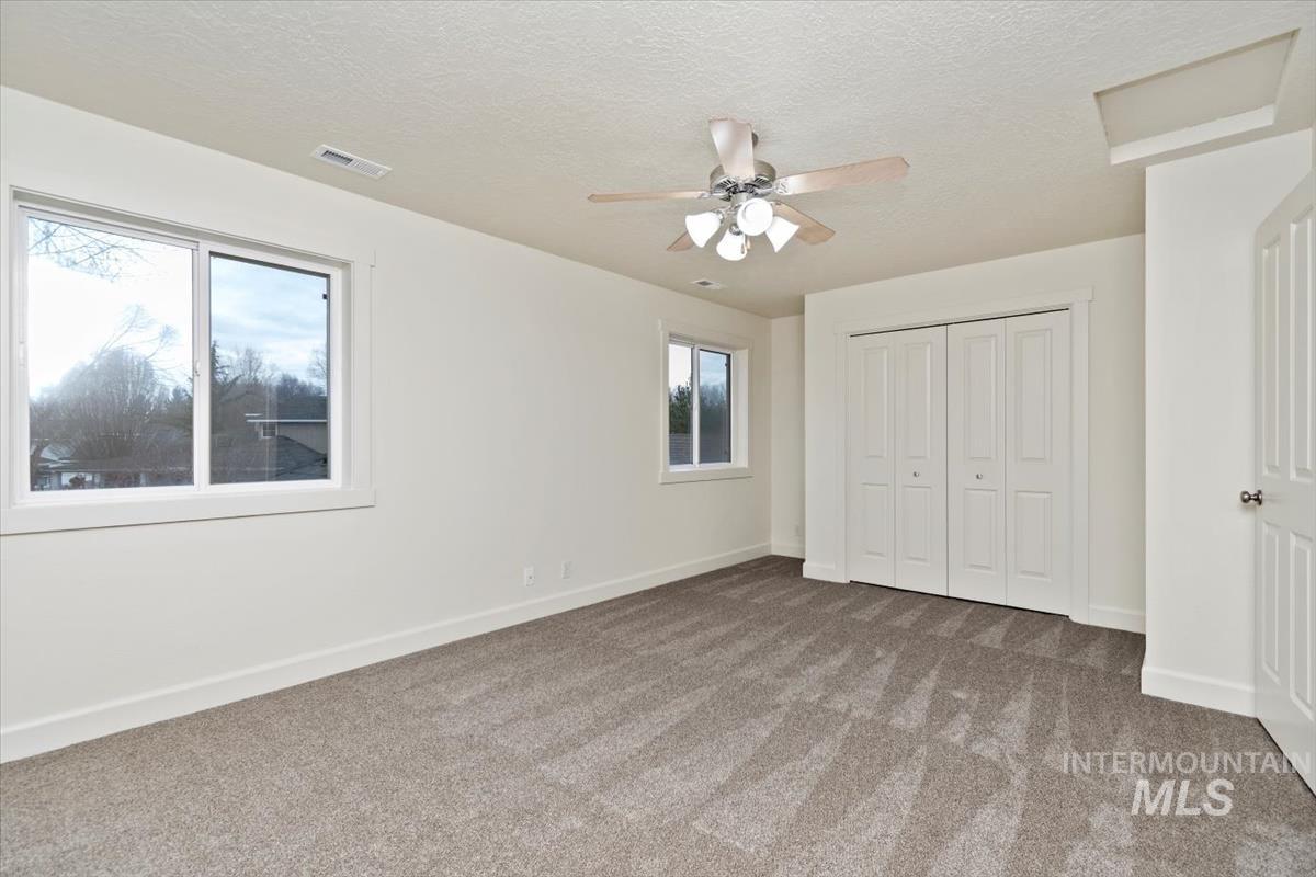 Unfurnished bedroom with carpet, a closet, a textured ceiling, and ceiling fan