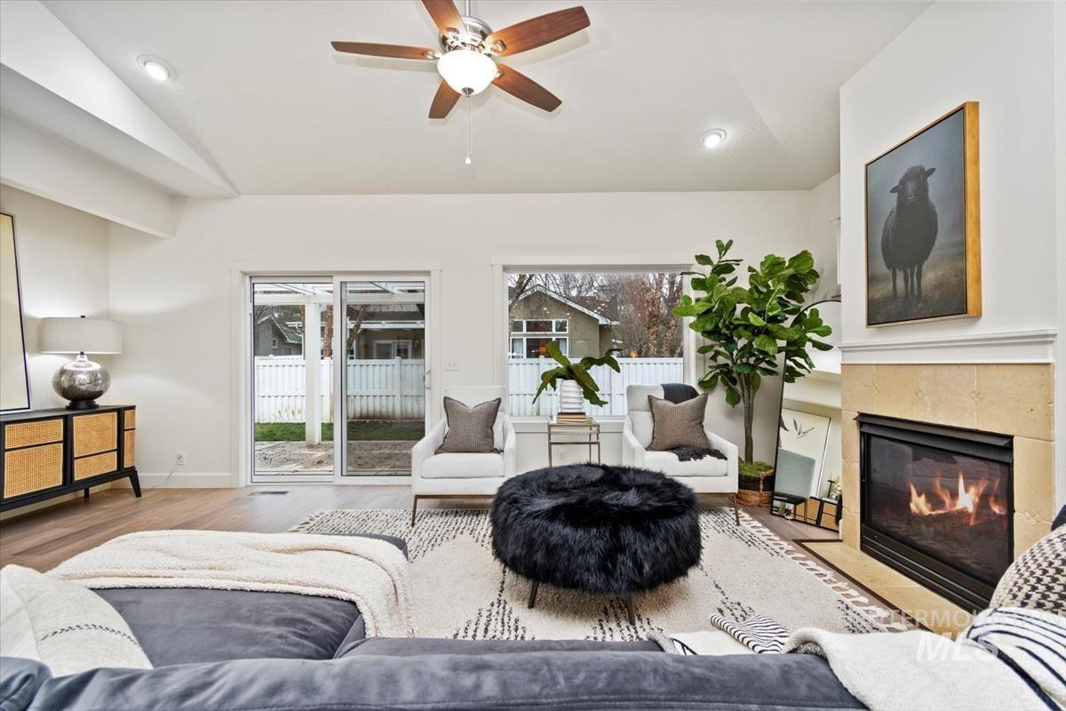 Living area featuring vaulted ceiling, healthy amount of natural light, ceiling fan, wood finished floors, and a tile fireplace