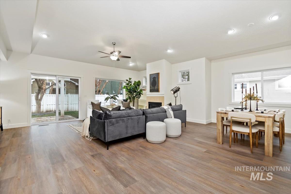 Living area with wood finished floors, ceiling fan, a tiled fireplace, and recessed lighting