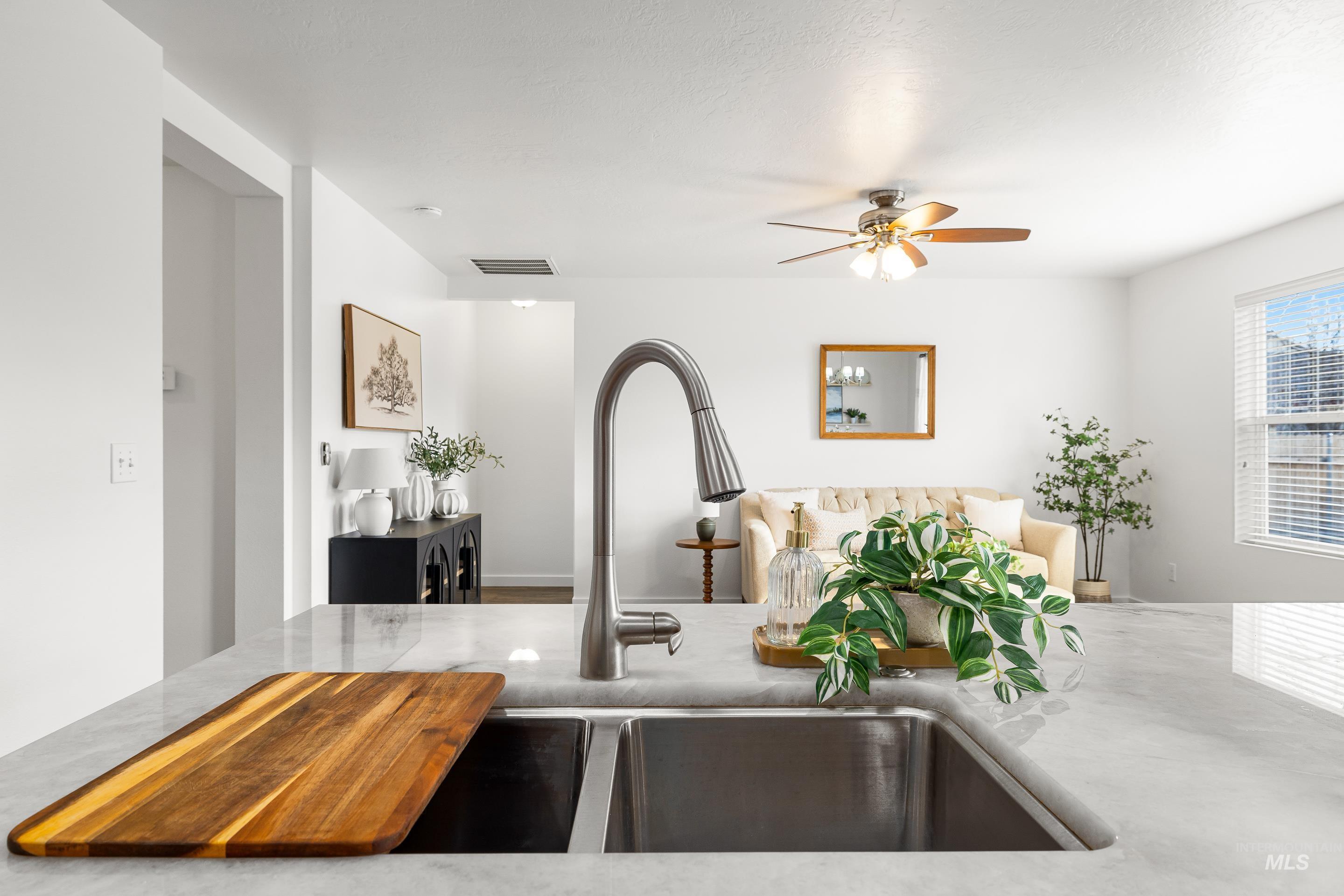 Kitchen view of ceiling fan and light stone counters