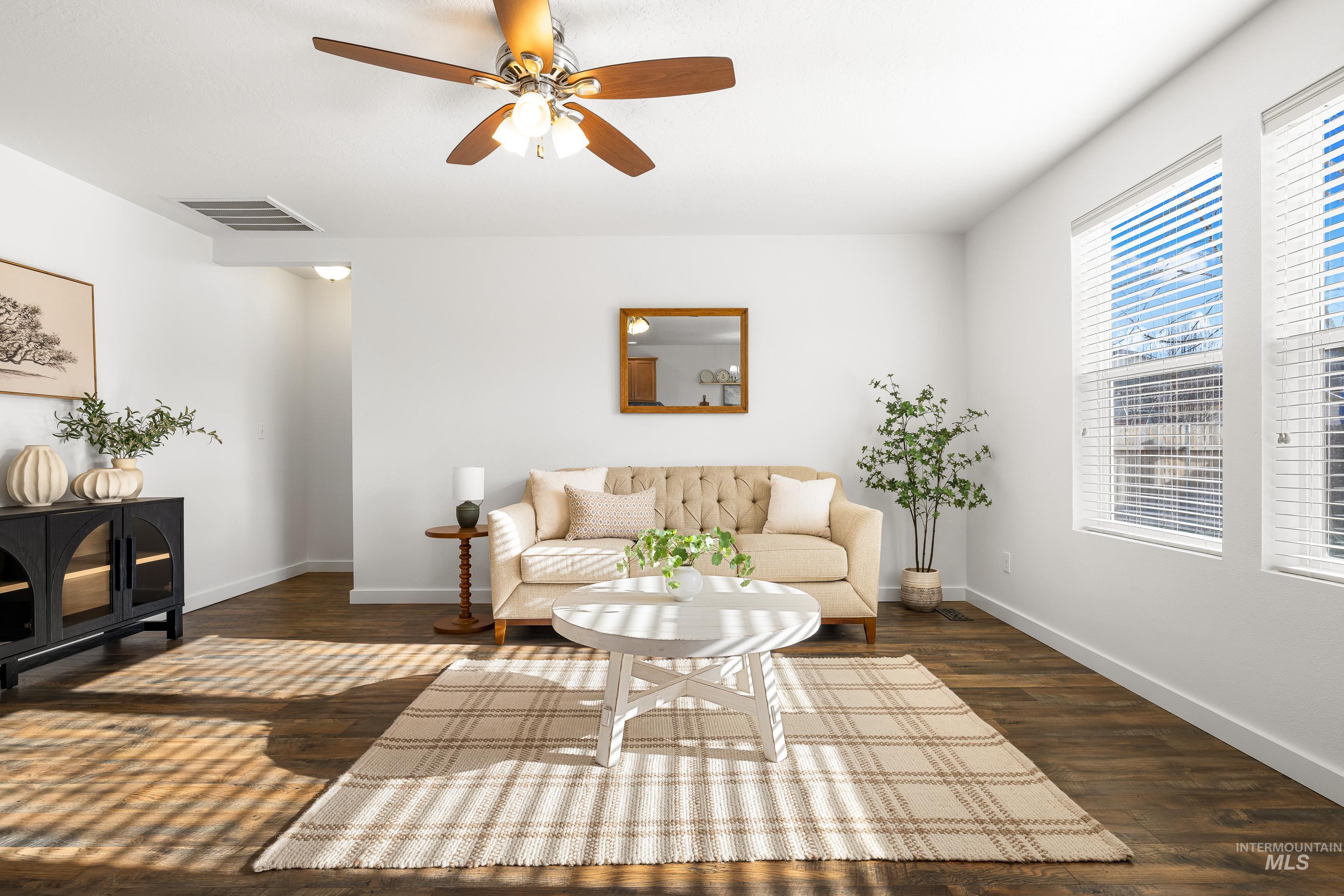 Living area with a ceiling fan and dark wood-style flooring