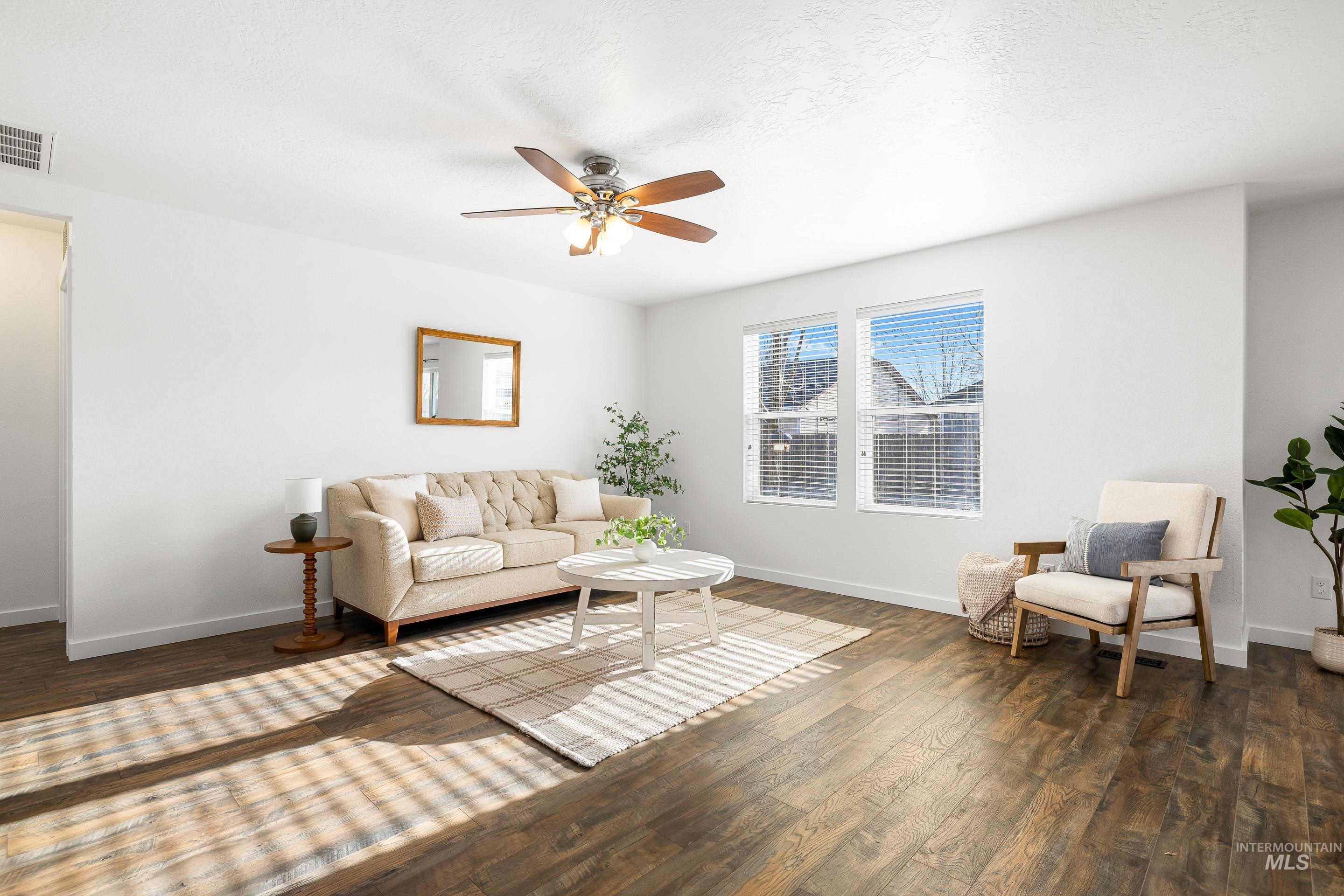 Living room with ceiling fan and dark wood-style floors