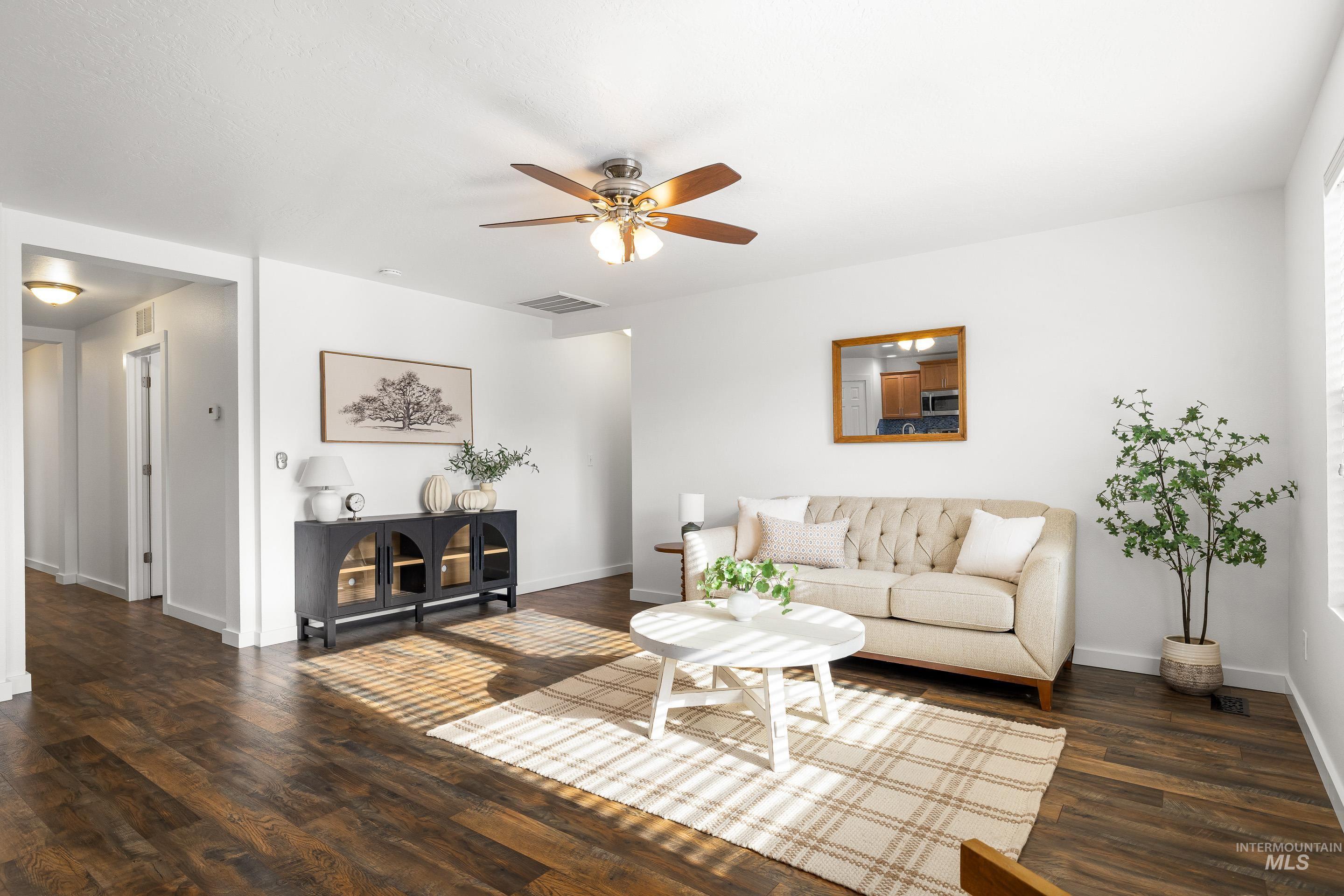 Living area with a ceiling fan and dark wood-type flooring