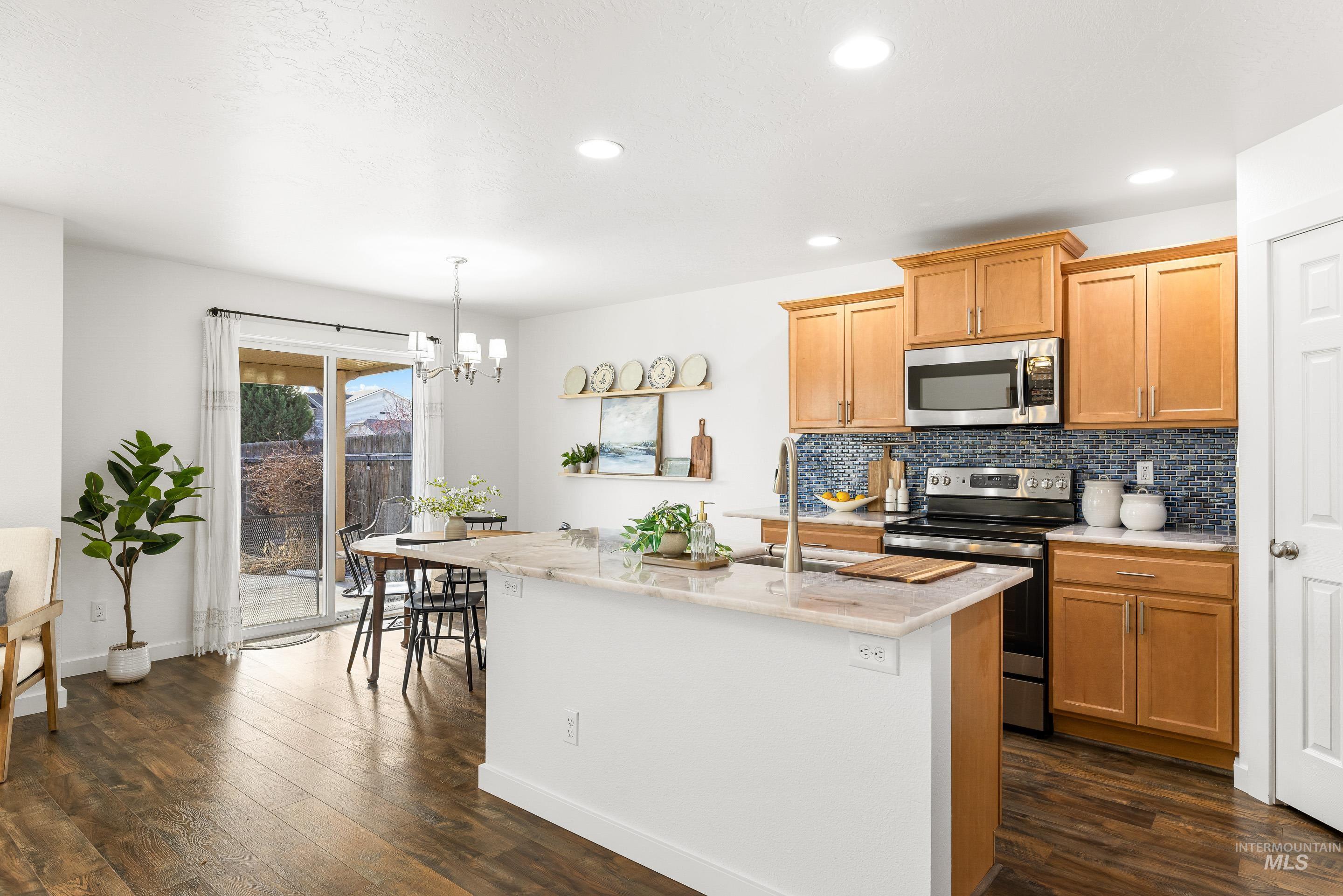 Kitchen with appliances with stainless steel finishes, tasteful backsplash, light stone counters, dark wood-style floors, and recessed lighting