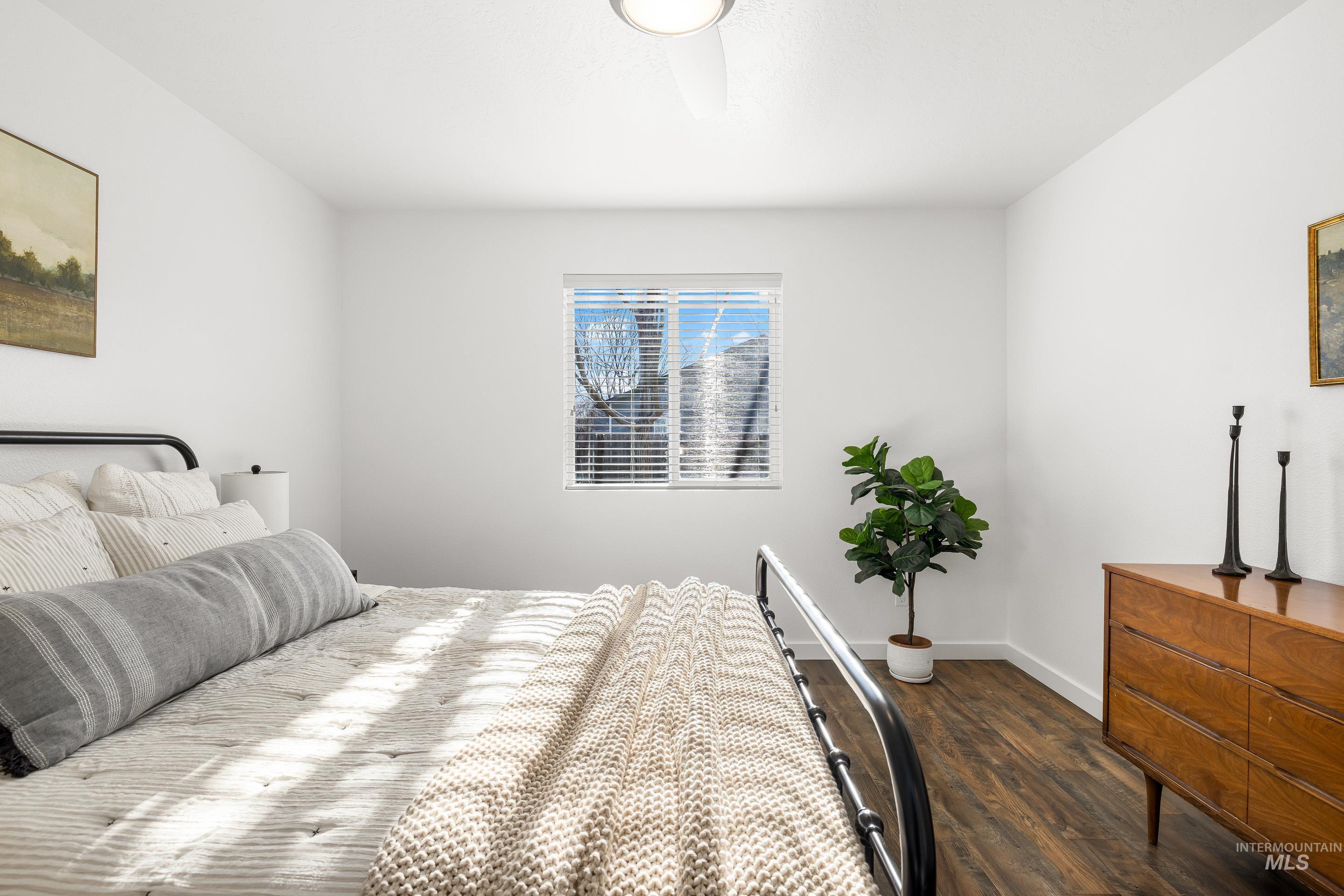 Bedroom with dark wood-type flooring and baseboards
