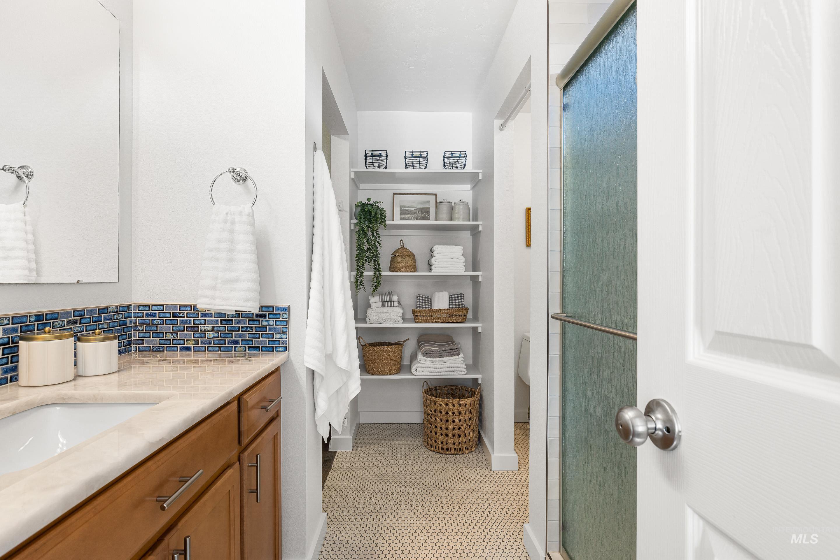 Bathroom with vanity, a shower stall, and backsplash