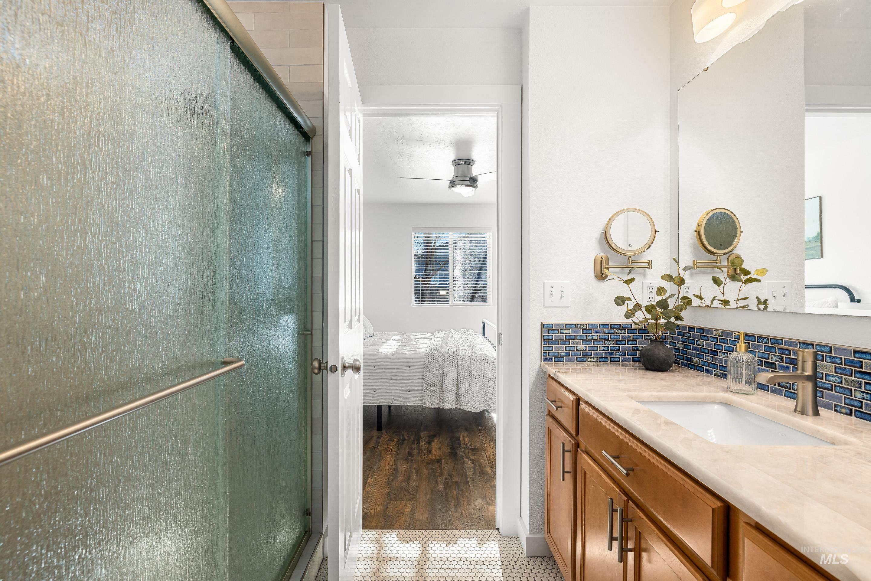Bathroom with a stall shower, vanity, ensuite bathroom, and backsplash
