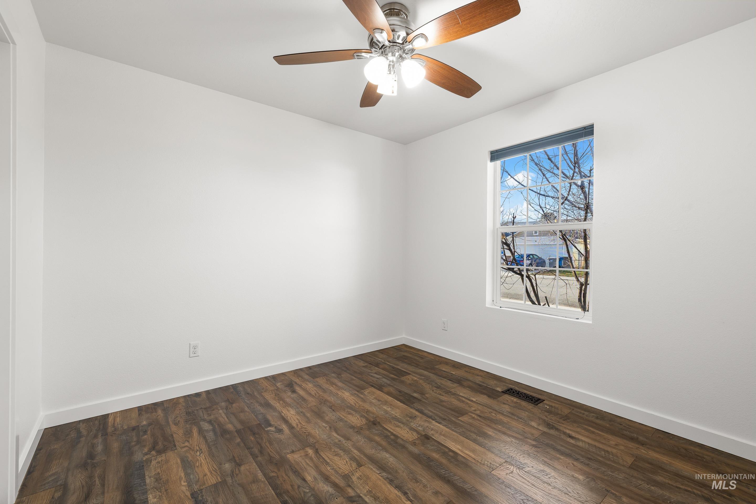 Empty room featuring dark wood finished floors and ceiling fan