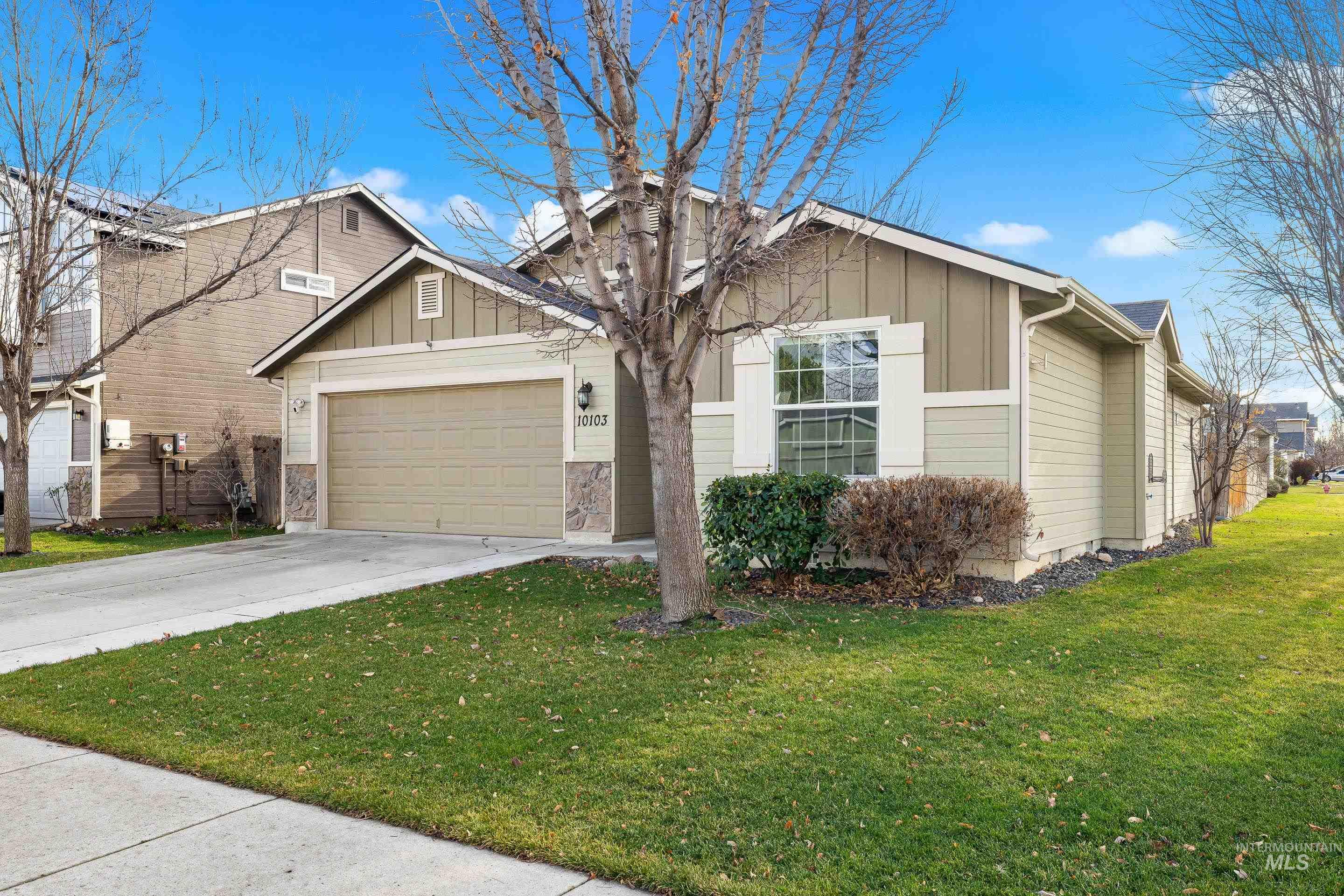 View of front of house featuring board and batten siding, concrete driveway, an attached garage, and a front lawn