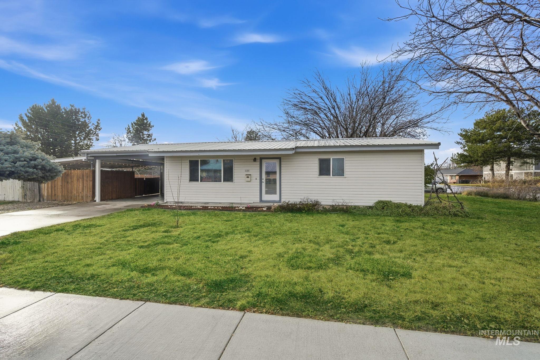 Single story home featuring concrete driveway, an attached carport, and a metal roof