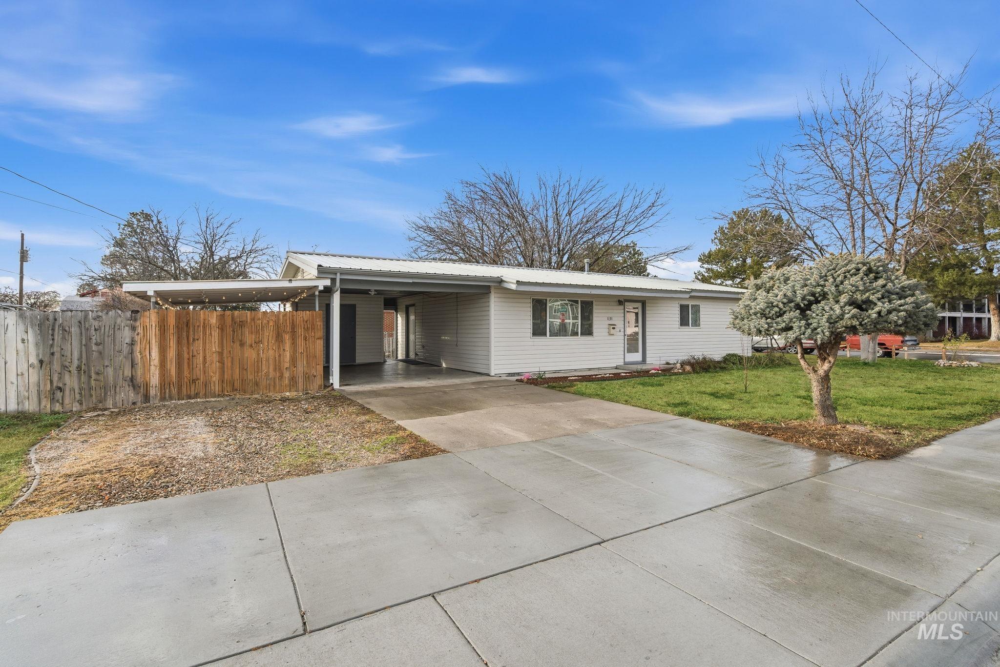 Ranch-style home with driveway, an attached carport, and a metal roof