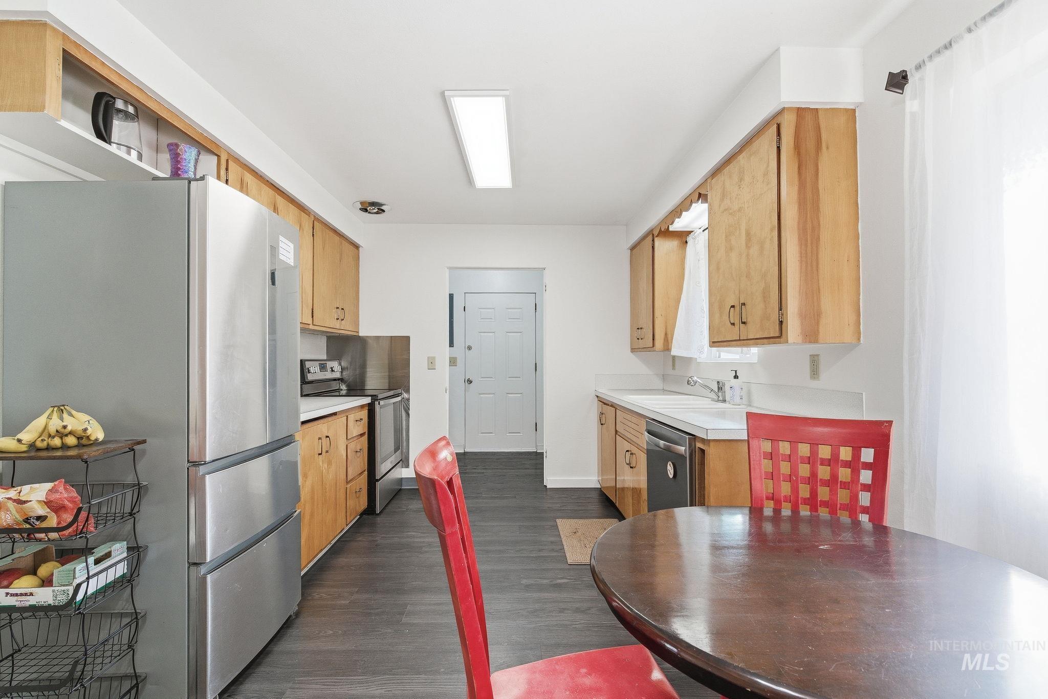 Kitchen with appliances with stainless steel finishes, dark wood-style floors, and light brown cabinets
