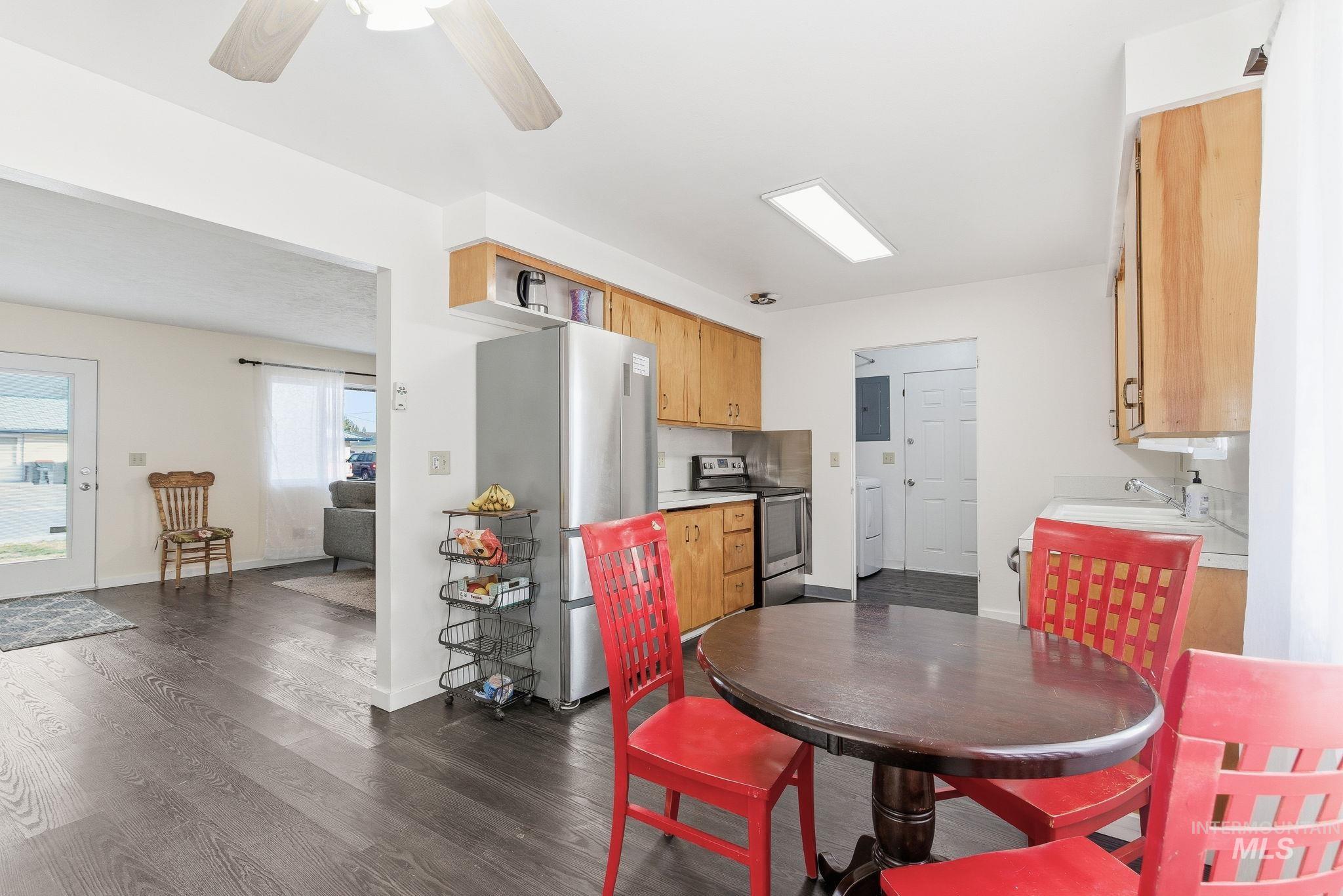 Kitchen featuring light countertops, appliances with stainless steel finishes, dark wood-type flooring, ceiling fan, and electric panel