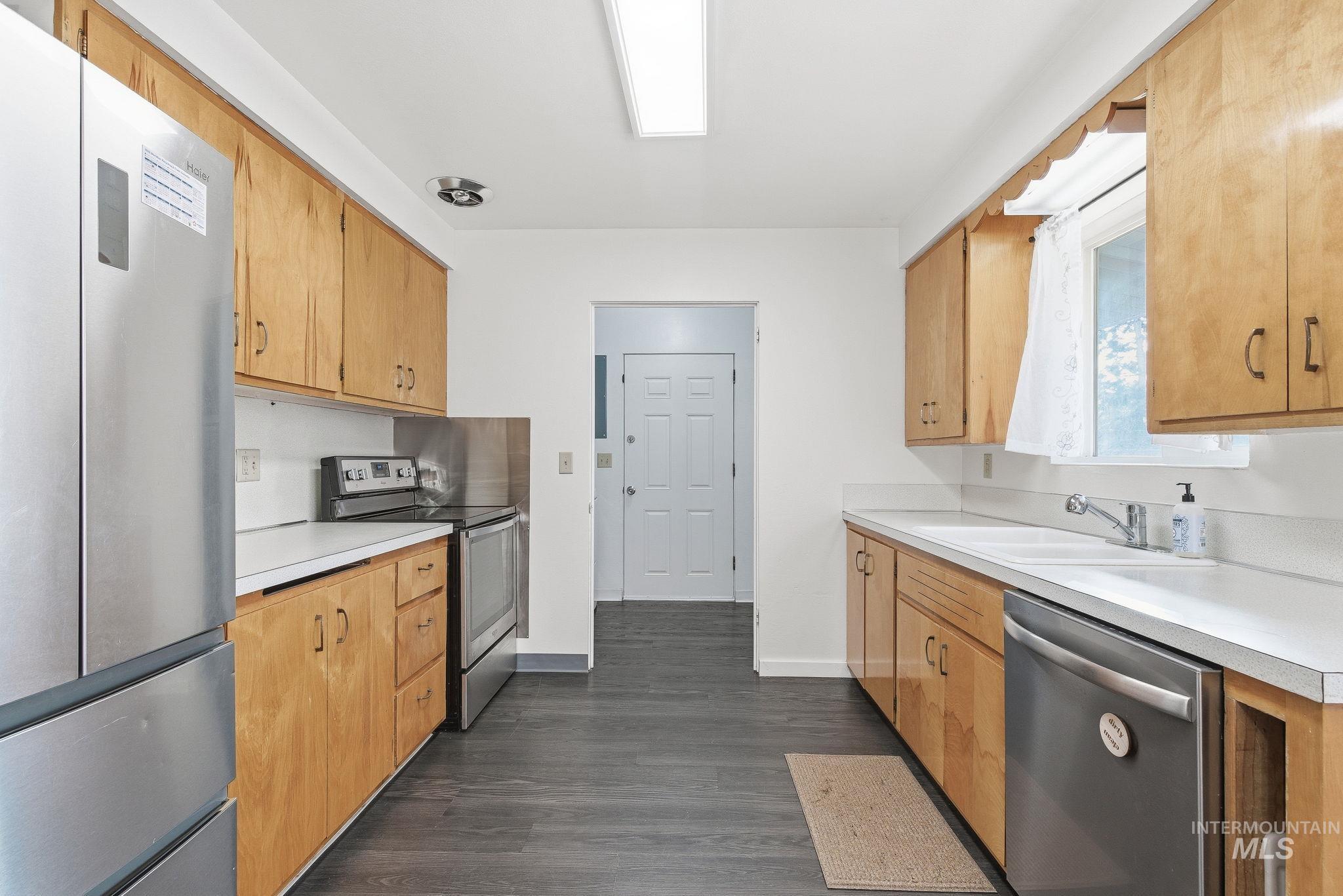 Kitchen with stainless steel appliances, light countertops, and dark wood finished floors