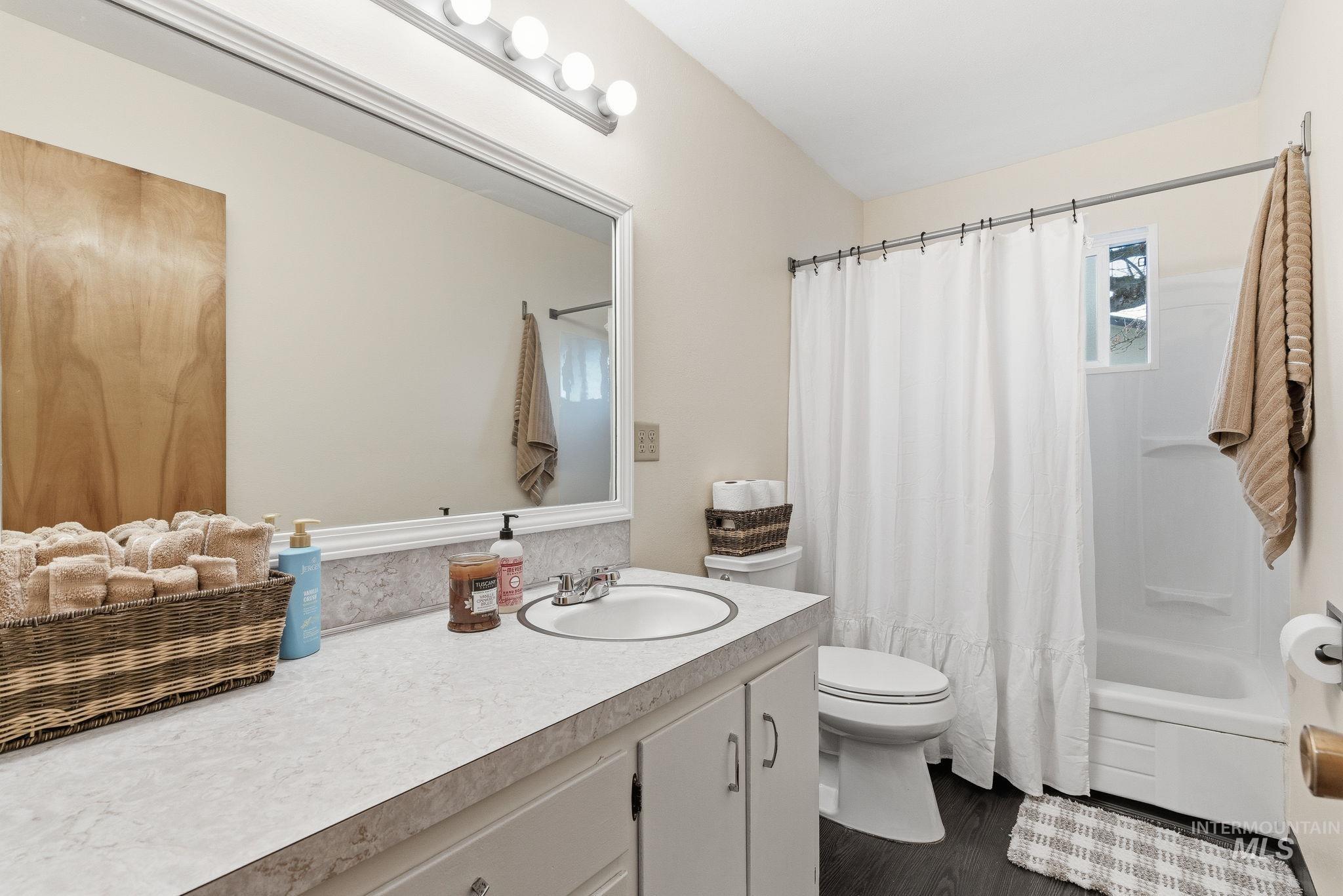 Full bath featuring shower / bathtub combination with curtain, vanity, and dark wood finished floors