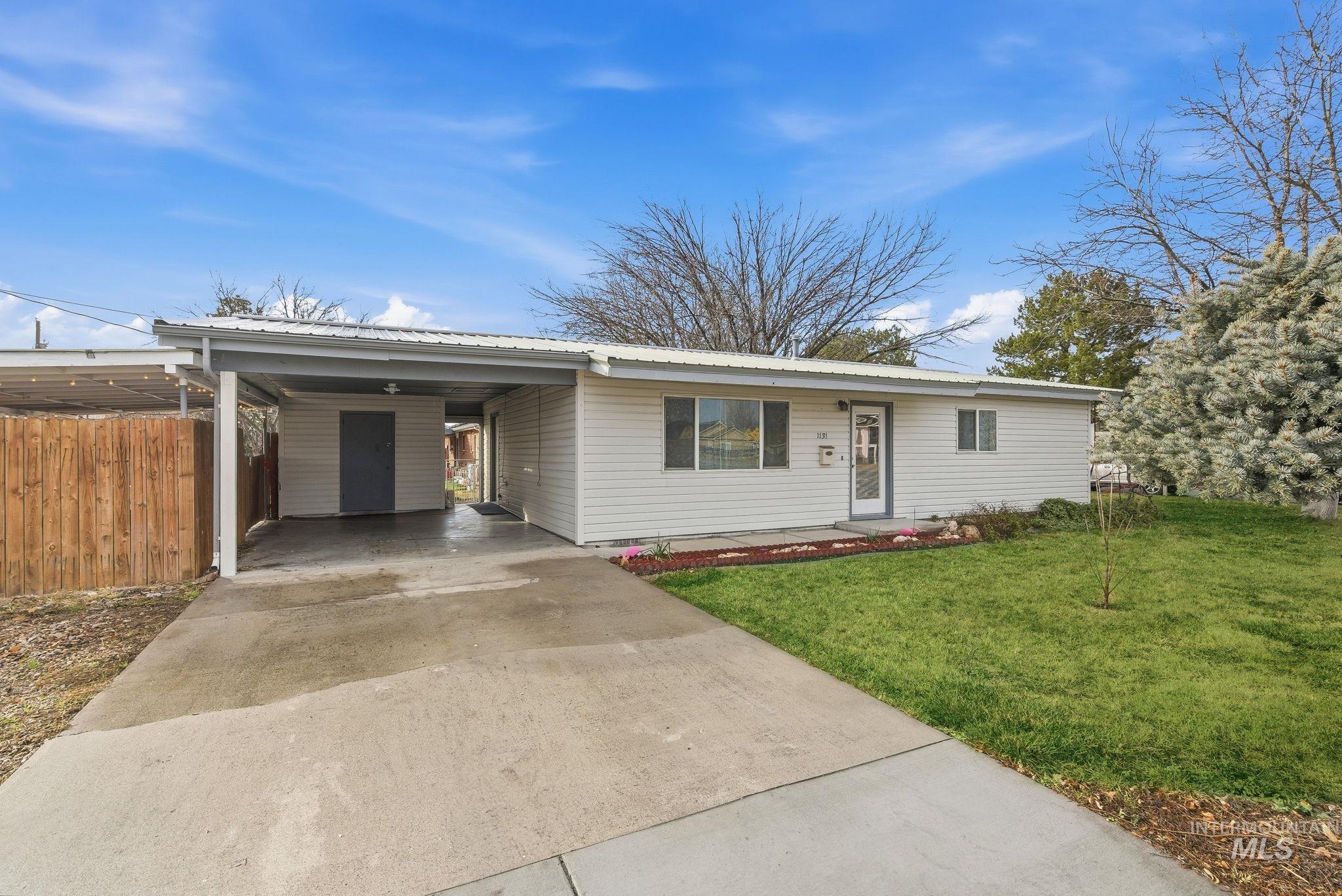 Ranch-style house with driveway, a carport, and a metal roof