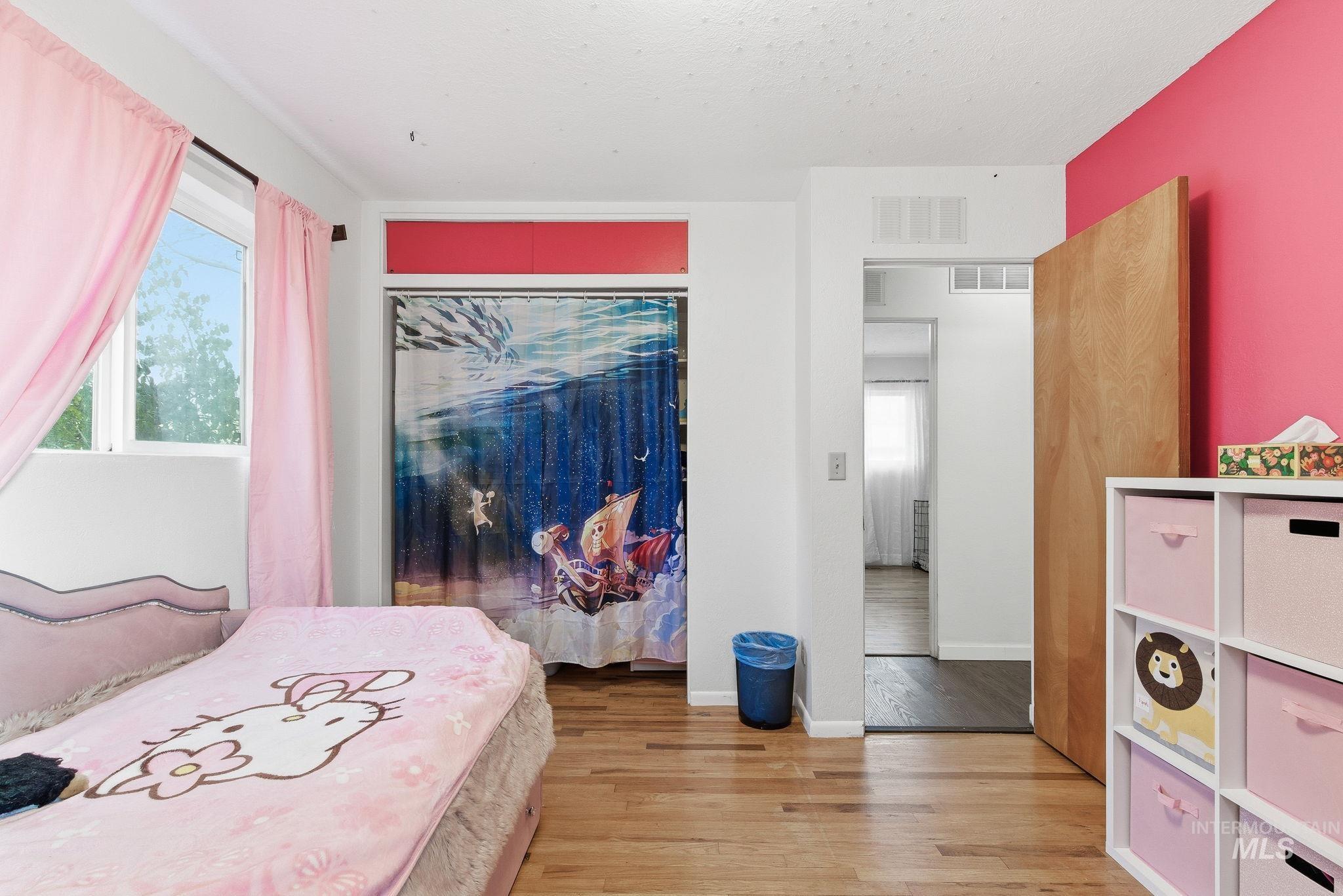 Bedroom with a closet, light wood-style flooring, and multiple windows
