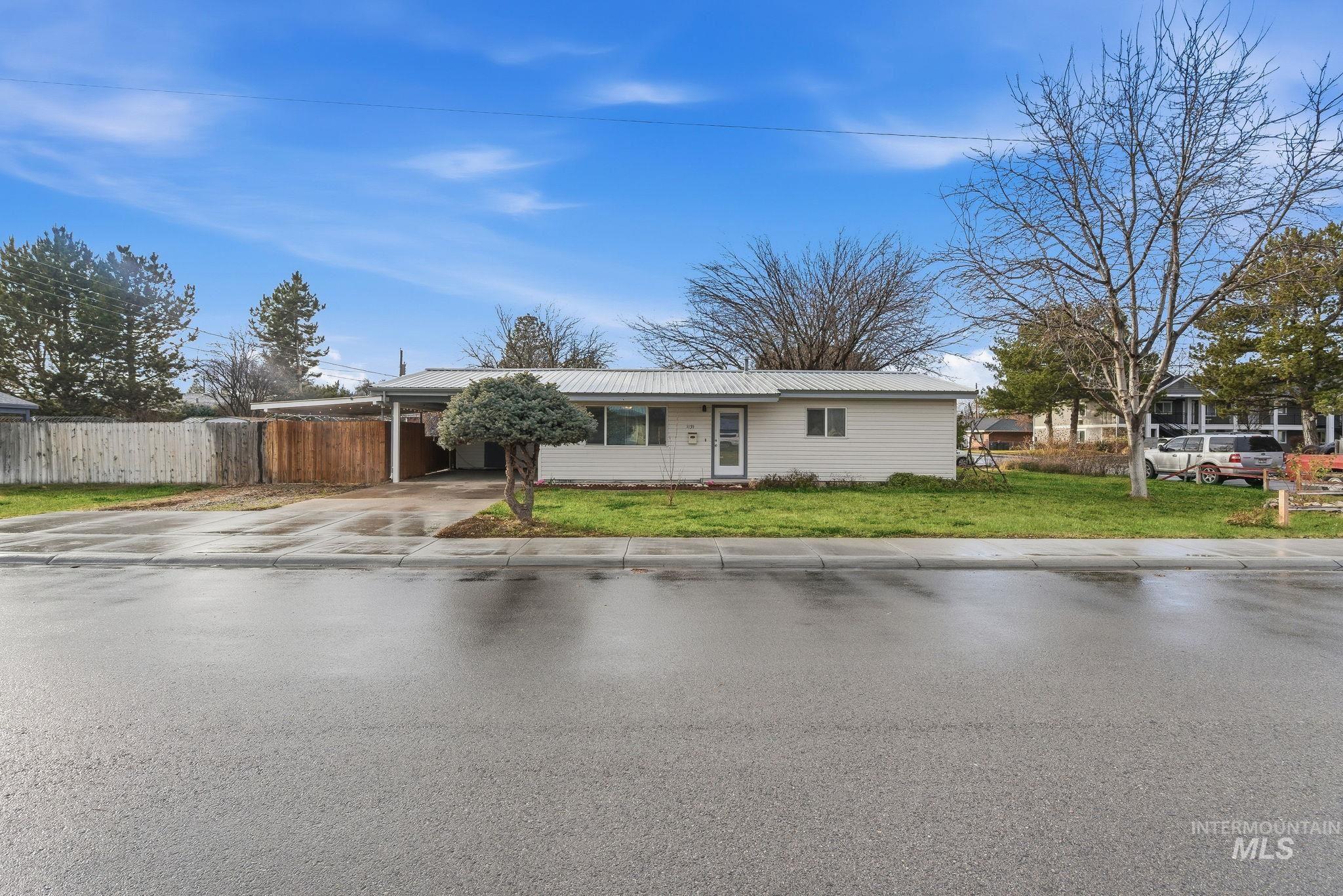 View of front of property with driveway, a carport, and a metal roof