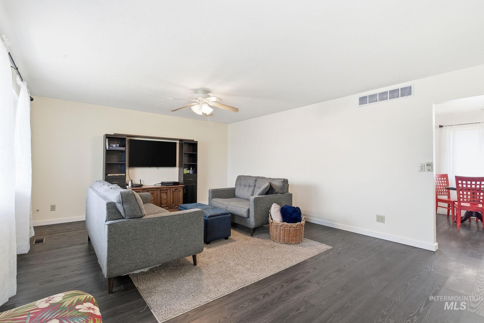 Living area featuring dark wood-type flooring and ceiling fan