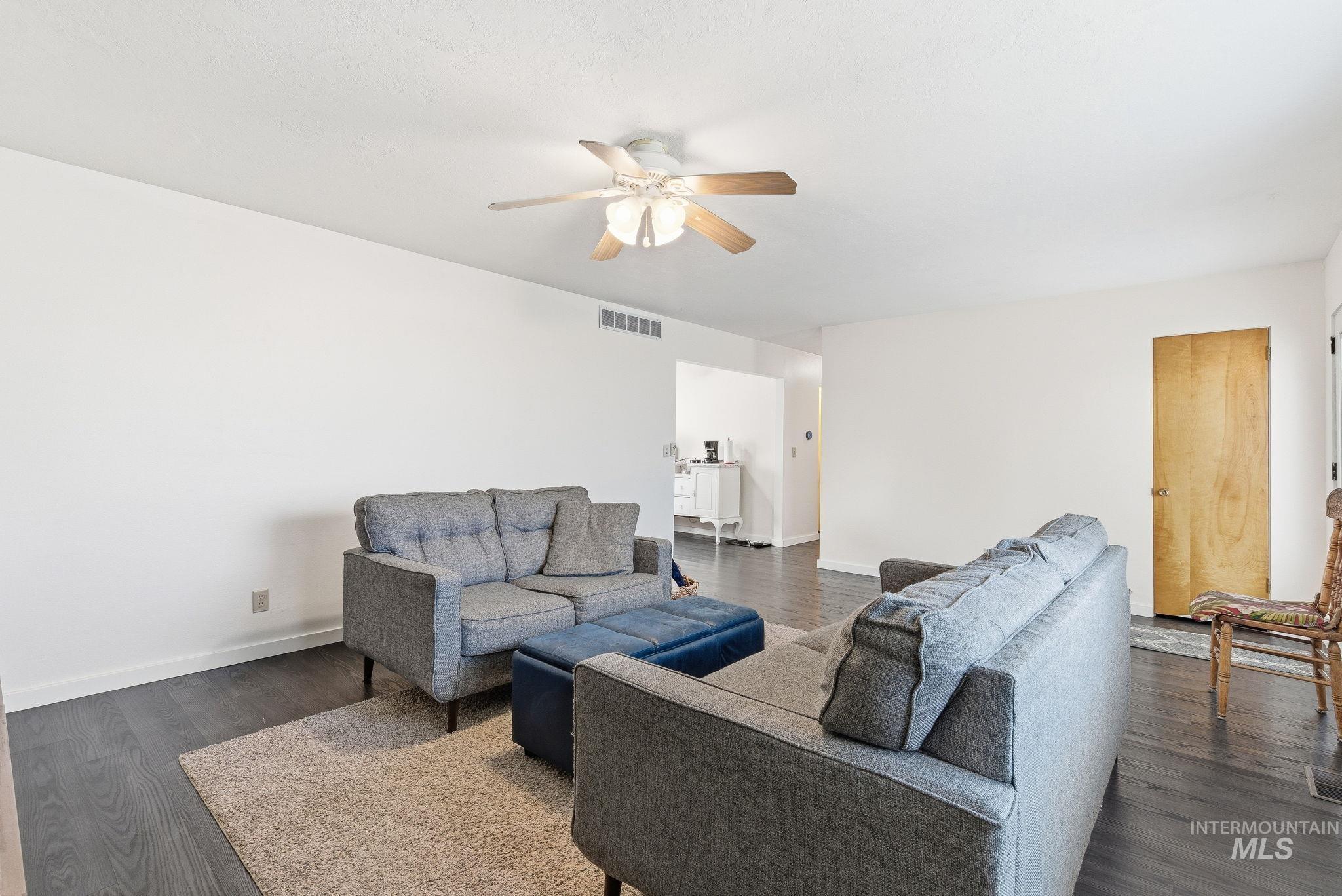 Living room featuring dark wood-type flooring and a ceiling fan