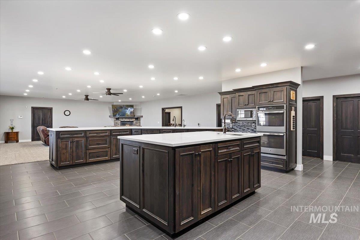 Kitchen featuring open floor plan, dark brown cabinets, recessed lighting, appliances with stainless steel finishes, and a ceiling fan