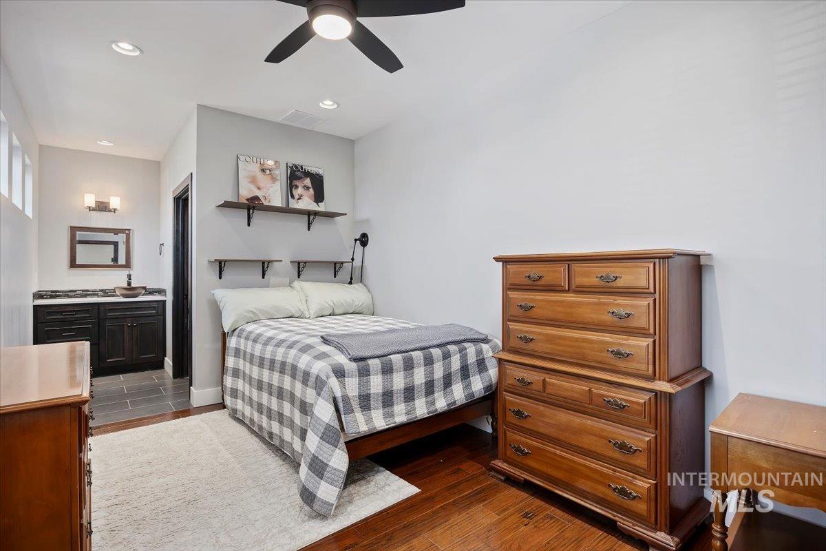 Bedroom with dark wood finished floors, connected bathroom, ceiling fan, and recessed lighting