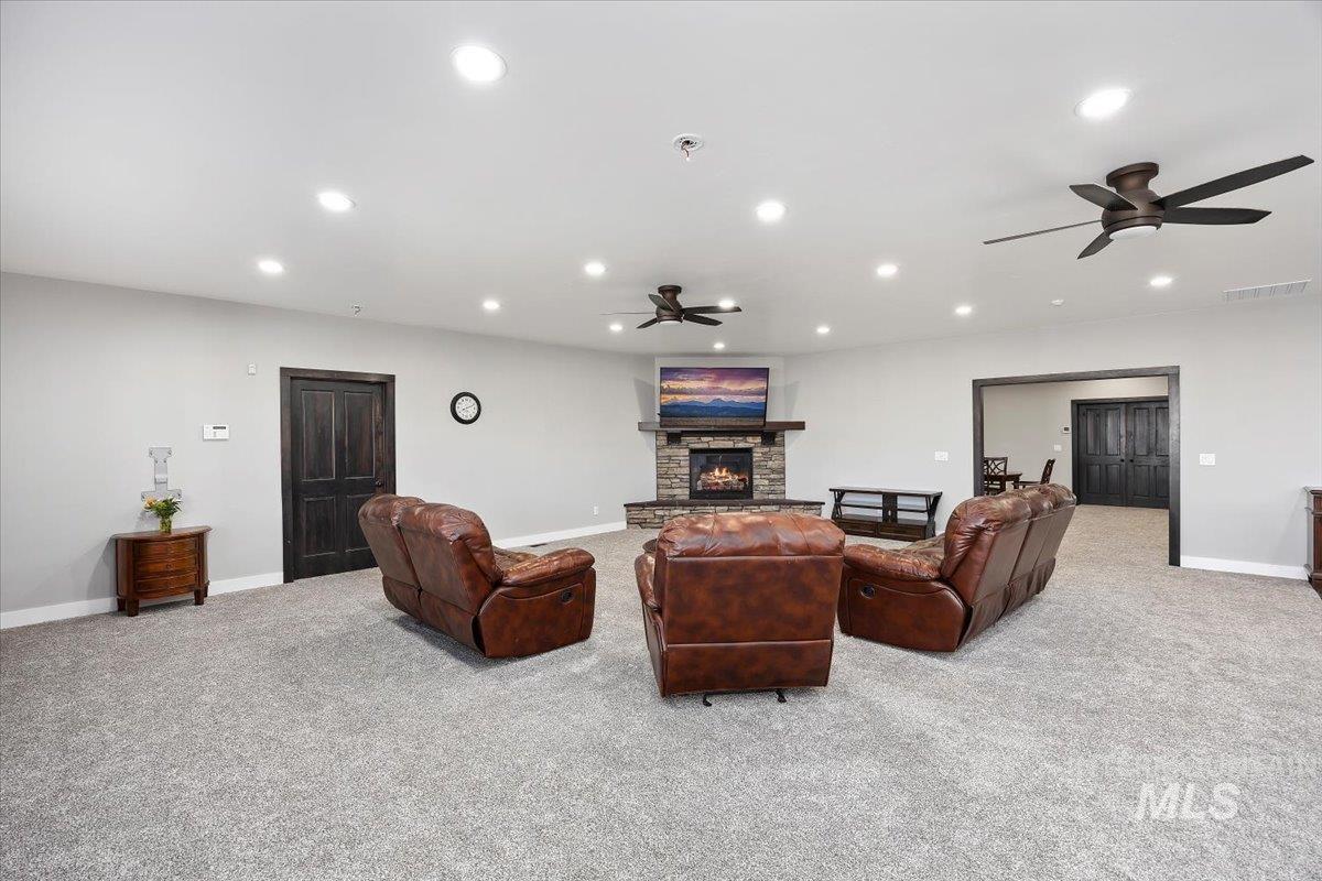 Living area with ceiling fan, light carpet, recessed lighting, and a fireplace