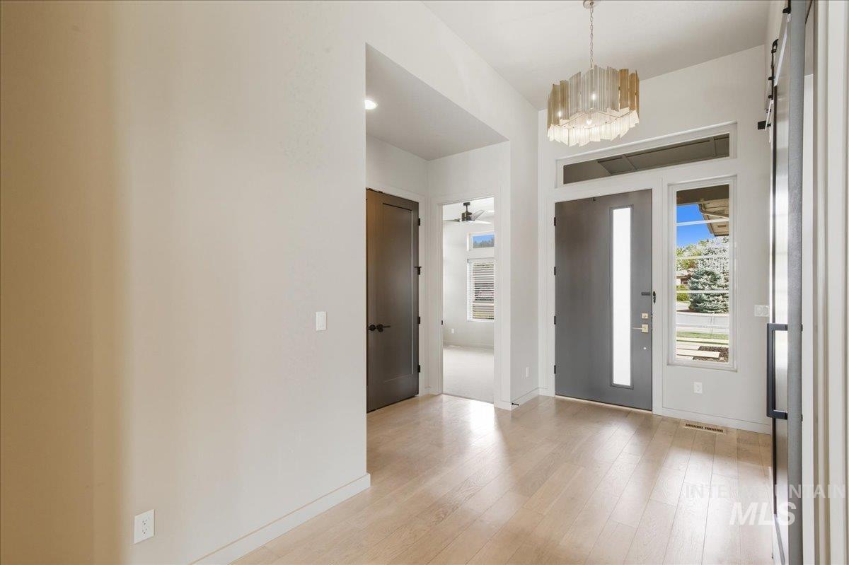 Entrance foyer featuring light wood-type flooring, a chandelier, and a ceiling fan