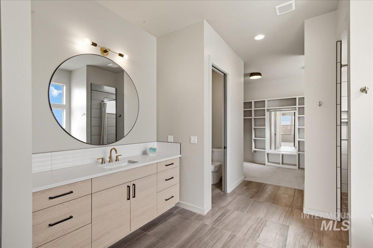 Full bathroom featuring a walk in closet, vanity, recessed lighting, and healthy amount of natural light