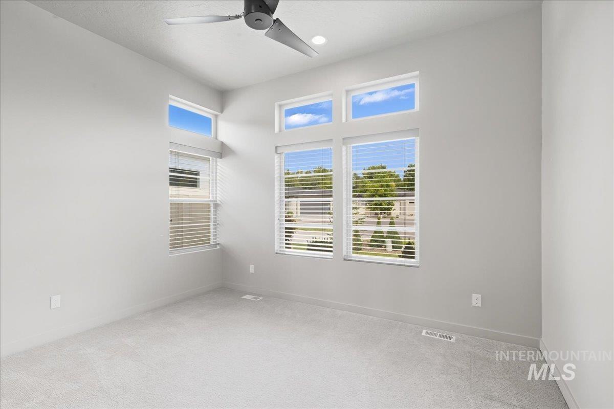 Unfurnished room featuring light colored carpet, plenty of natural light, and ceiling fan