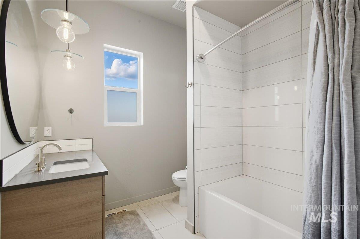 Bathroom with shower / tub combo, double vanity, and light tile patterned floors