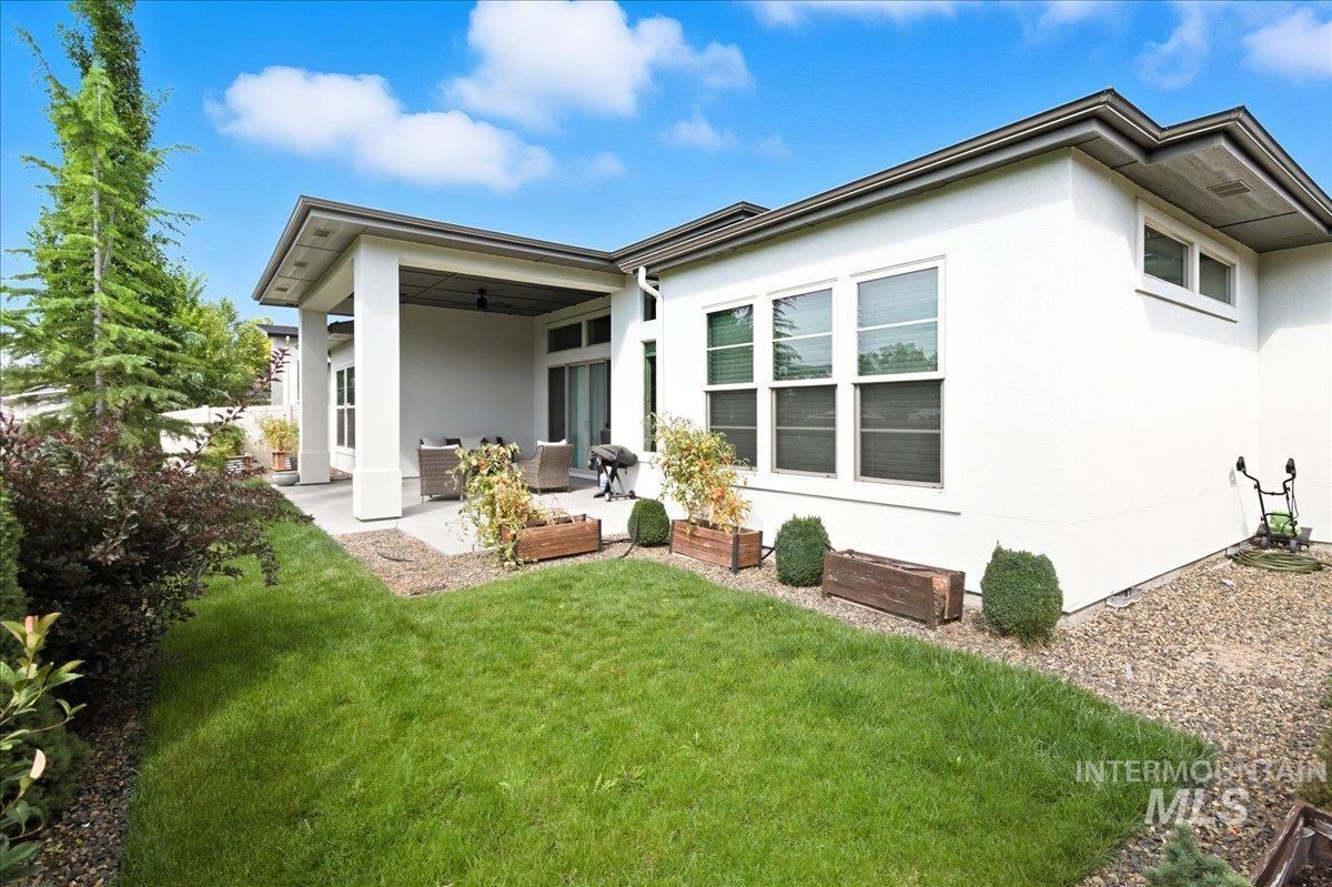 Back of house featuring stucco siding, a lawn, and a patio