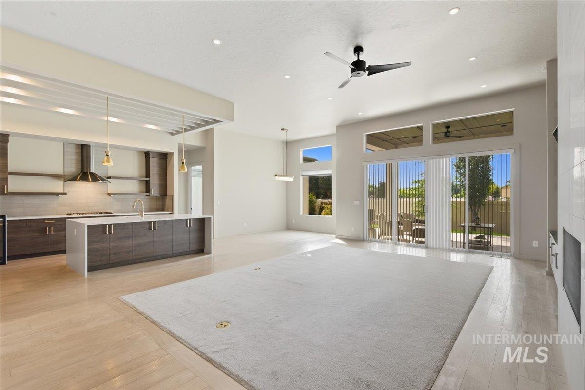 Unfurnished living room featuring ceiling fan, a fireplace, light wood finished floors, and recessed lighting