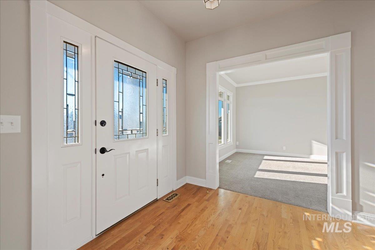 Foyer featuring healthy amount of natural light, wood finished floors, and ornamental molding