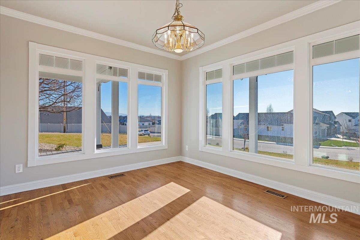 Unfurnished dining area featuring ornamental molding, wood finished floors, and a chandelier