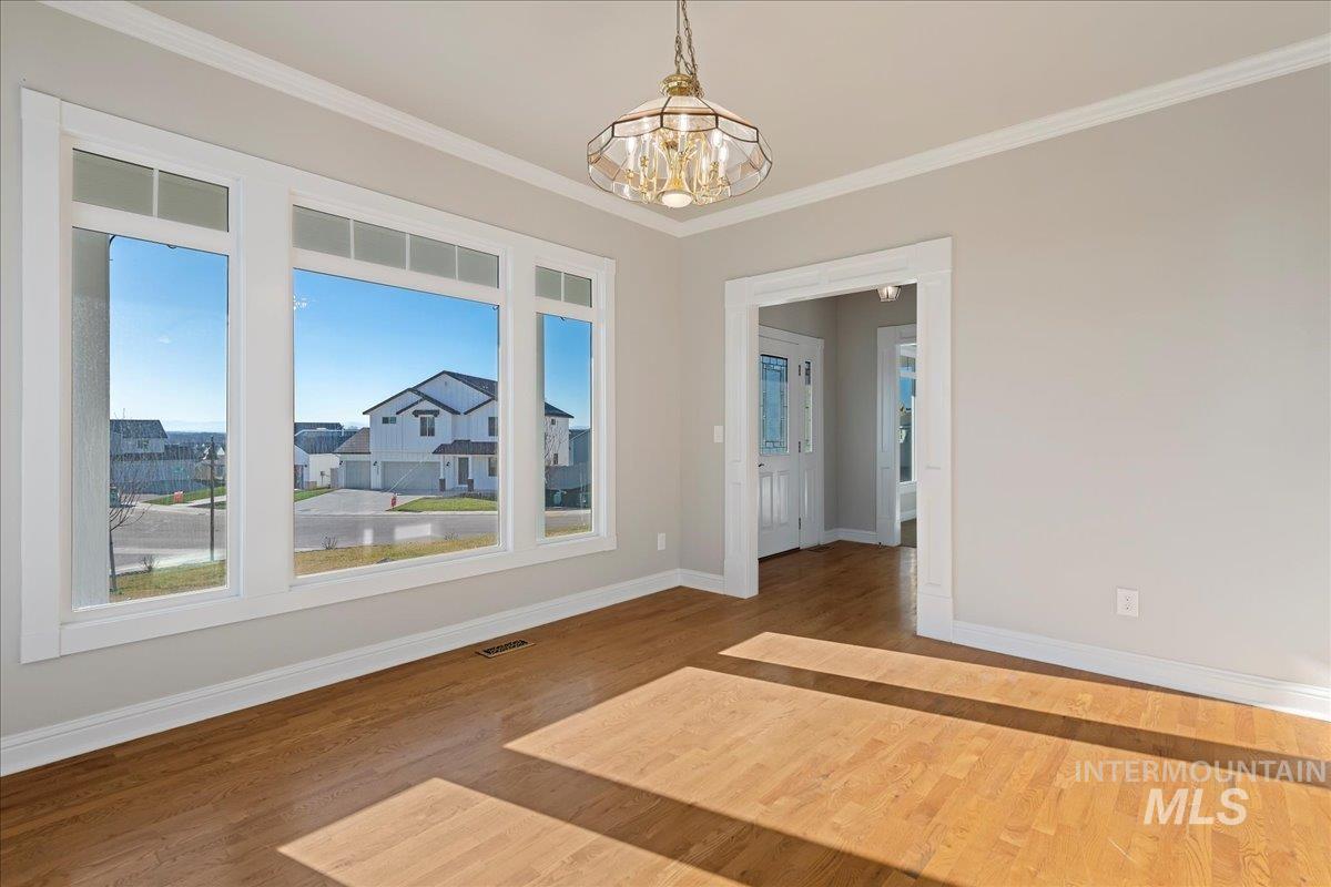 Unfurnished dining area with ornamental molding, a chandelier, and wood finished floors