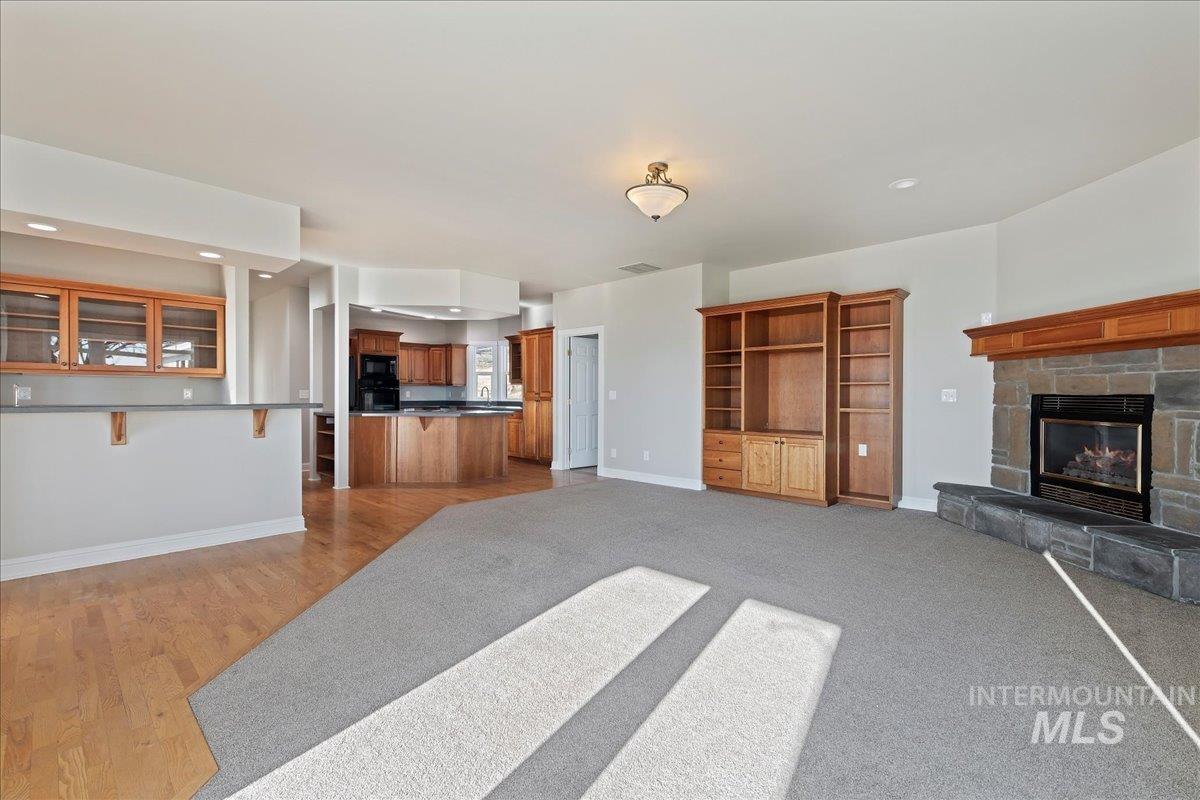 Unfurnished living room with a stone fireplace, recessed lighting, and light wood-style floors